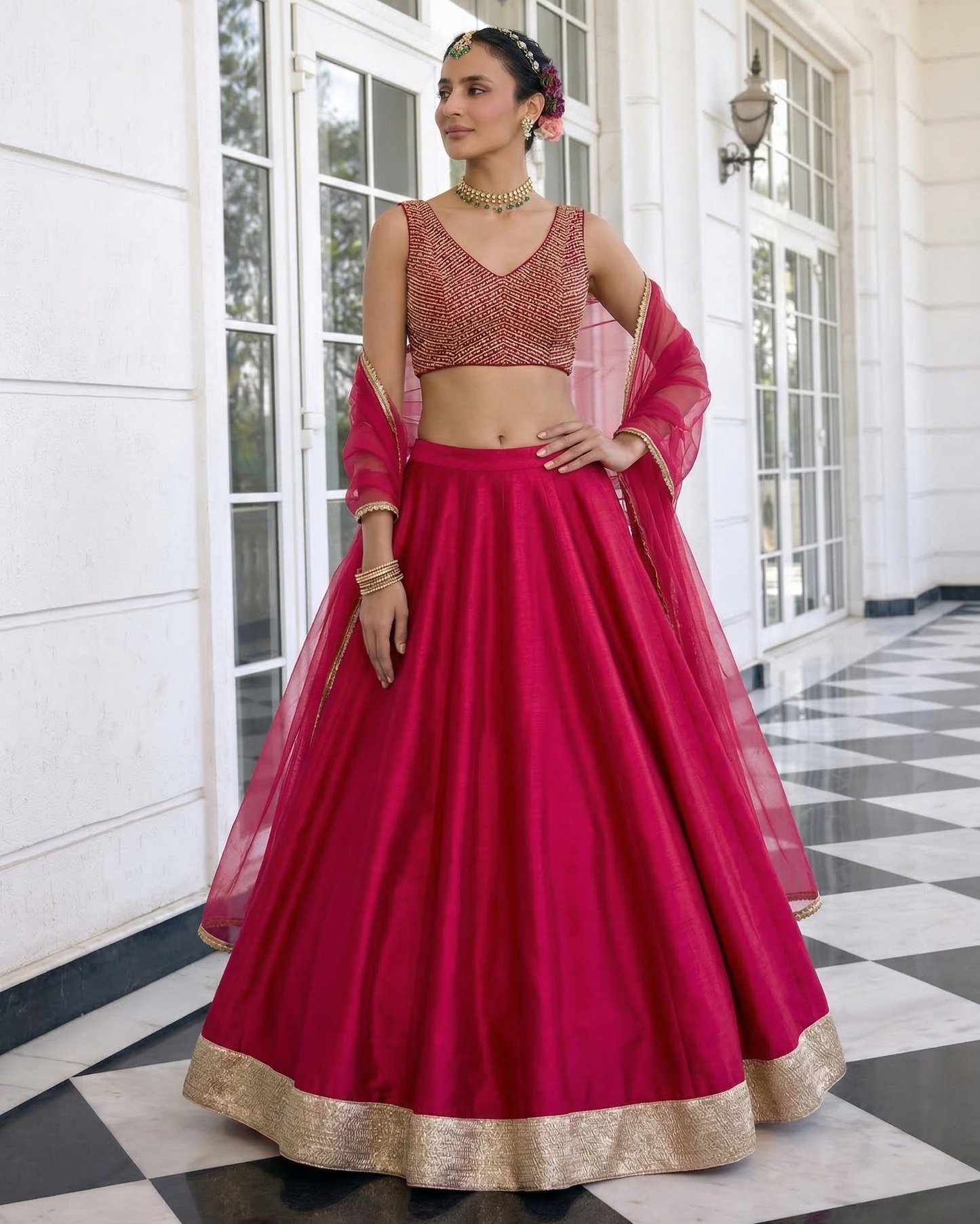 Woman in a bright pink traditional outfit with gold details standing in a well-lit room.