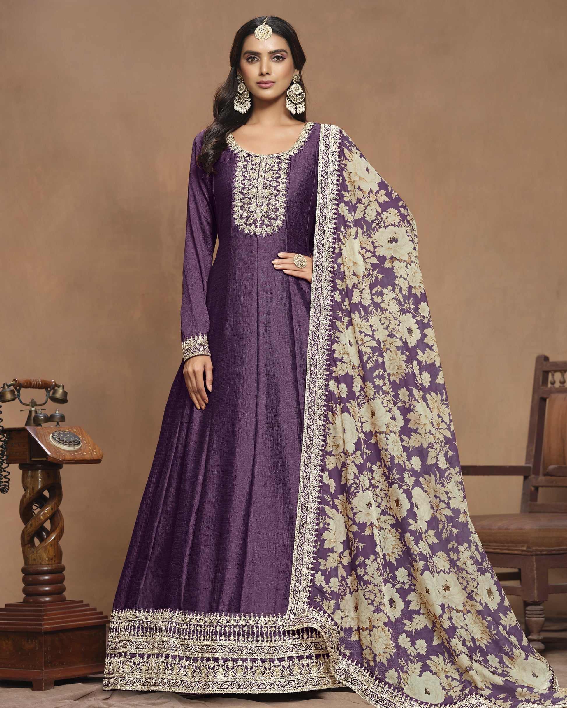 Woman wearing a purple traditional outfit with a floral shawl against a brown background