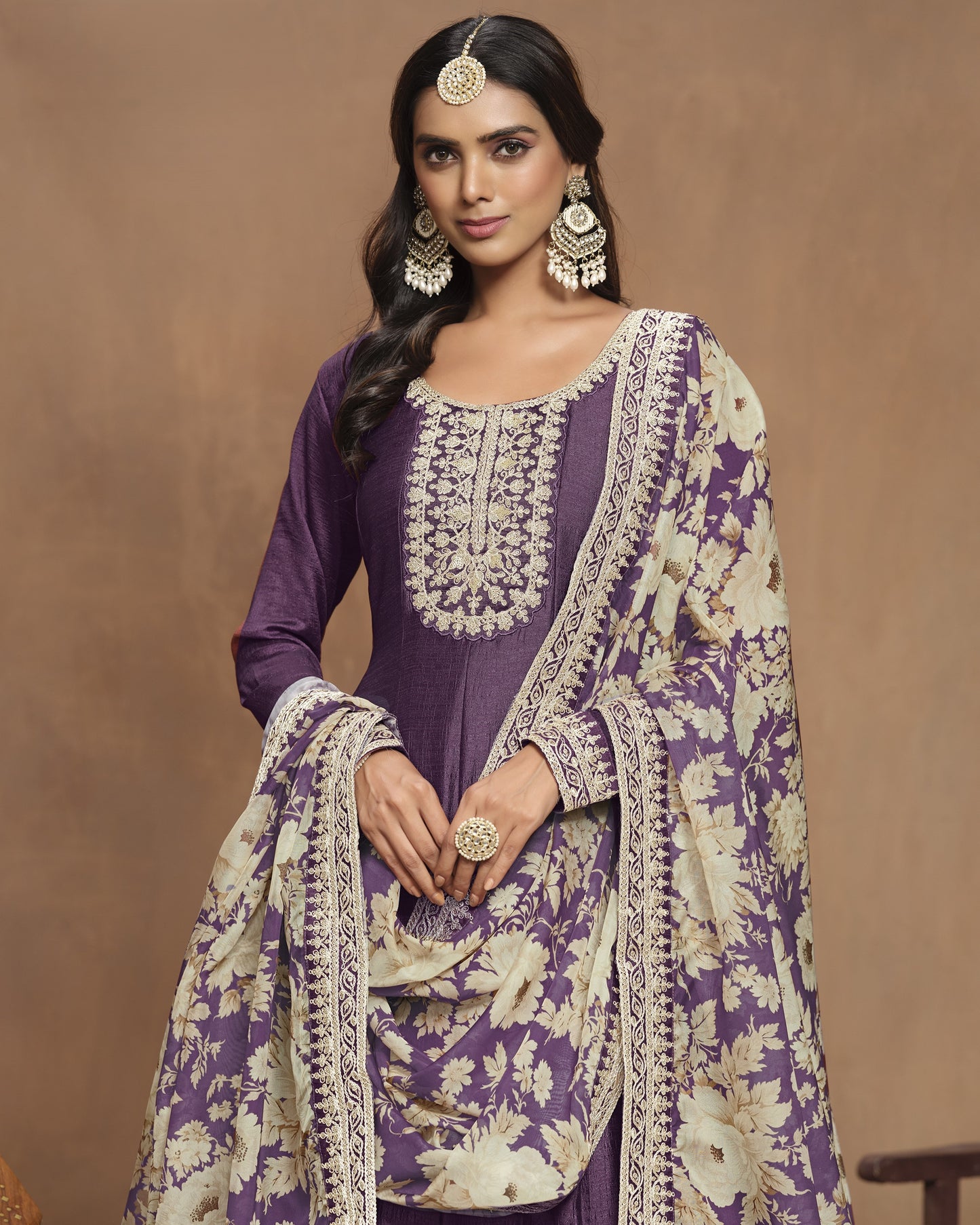 Woman wearing a traditional outfit with purple and beige patterns on a brown background