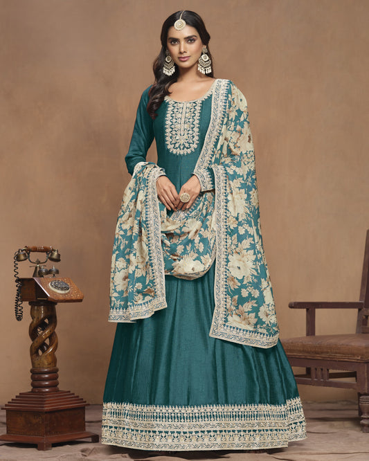 Woman wearing a teal traditional outfit with a floral shawl in a vintage setting.