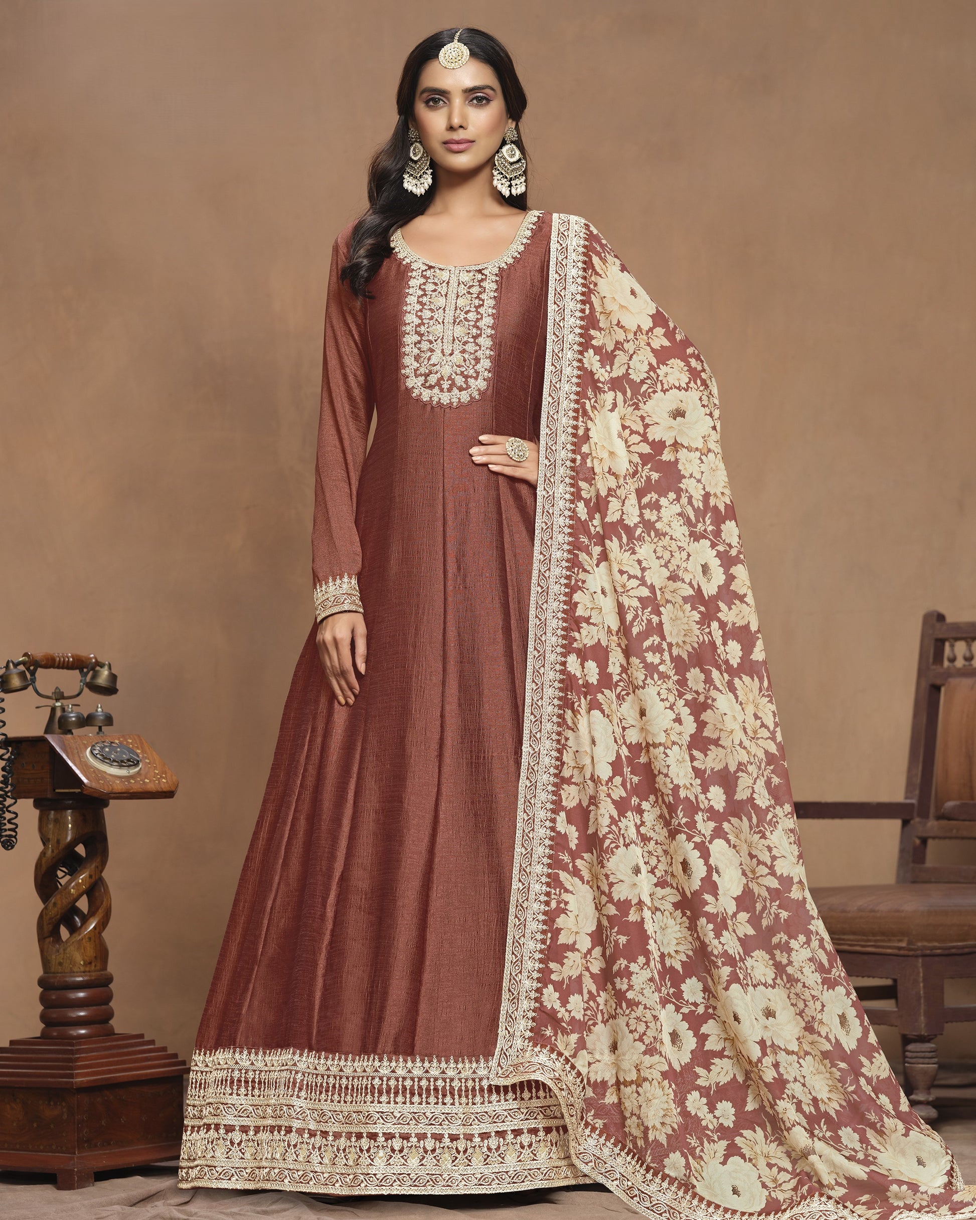 Woman wearing a traditional maroon and cream embroidered outfit with a matching dupatta against a beige background.