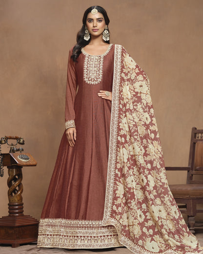 Woman wearing a traditional maroon and cream embroidered outfit with a matching dupatta against a beige background.