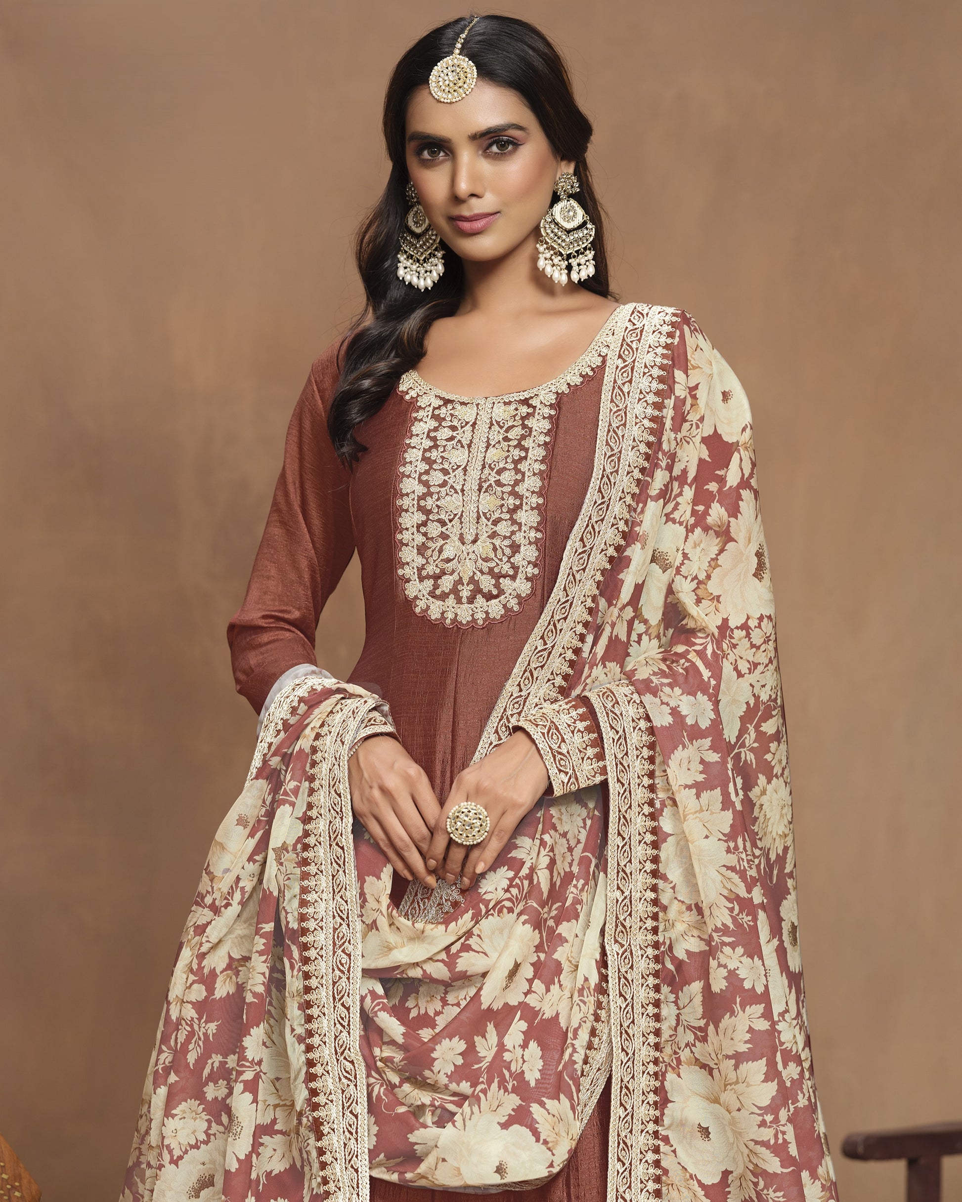 Woman wearing a traditional outfit with intricate embroidery on a brown background