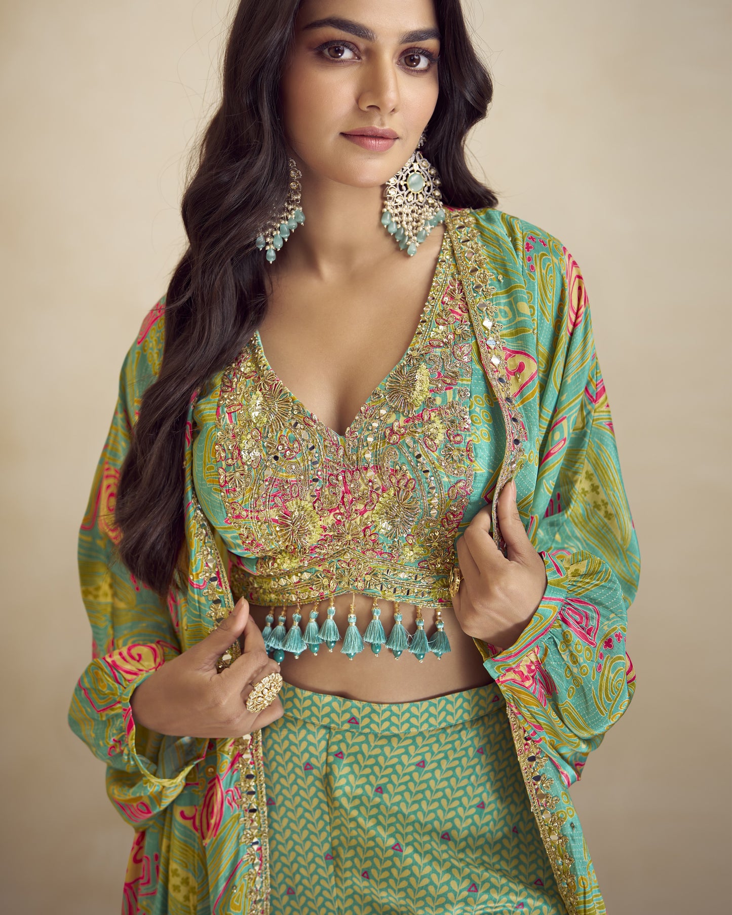 Woman wearing a traditional green and multicolored outfit with jewelry against a beige background
