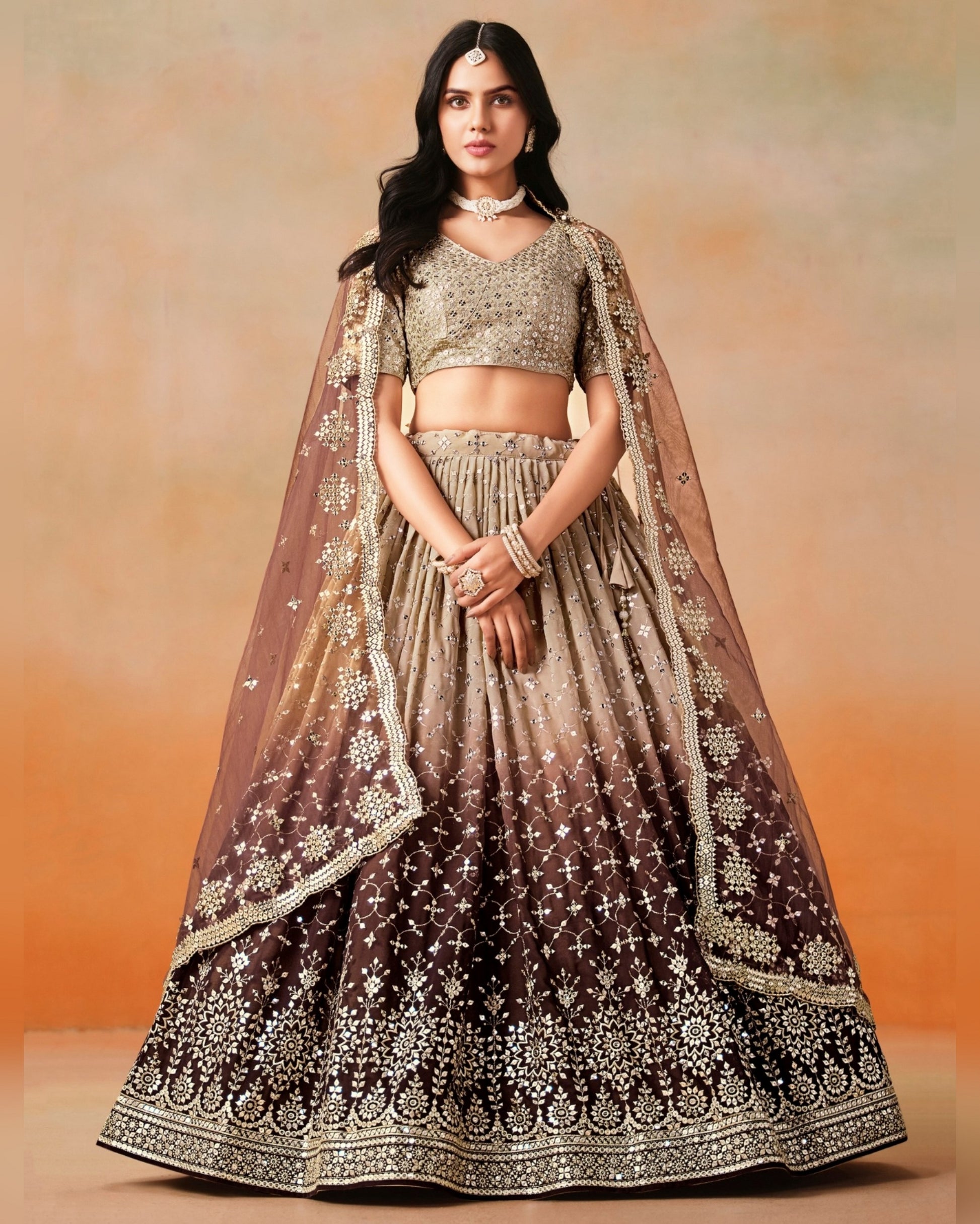 Woman wearing a traditional outfit with a brown and beige lehenga against an orange background
