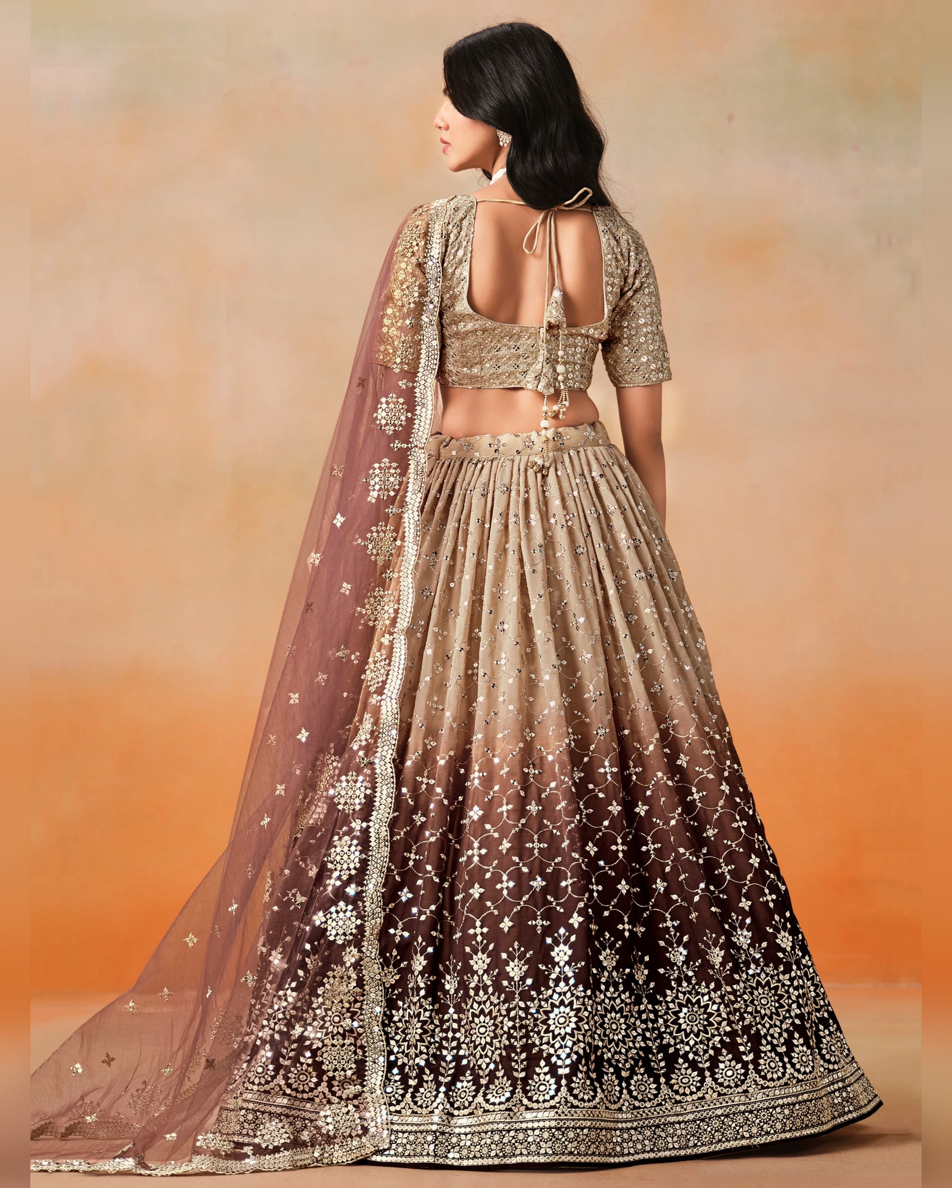 Woman wearing a traditional embroidered lehenga with a plain background