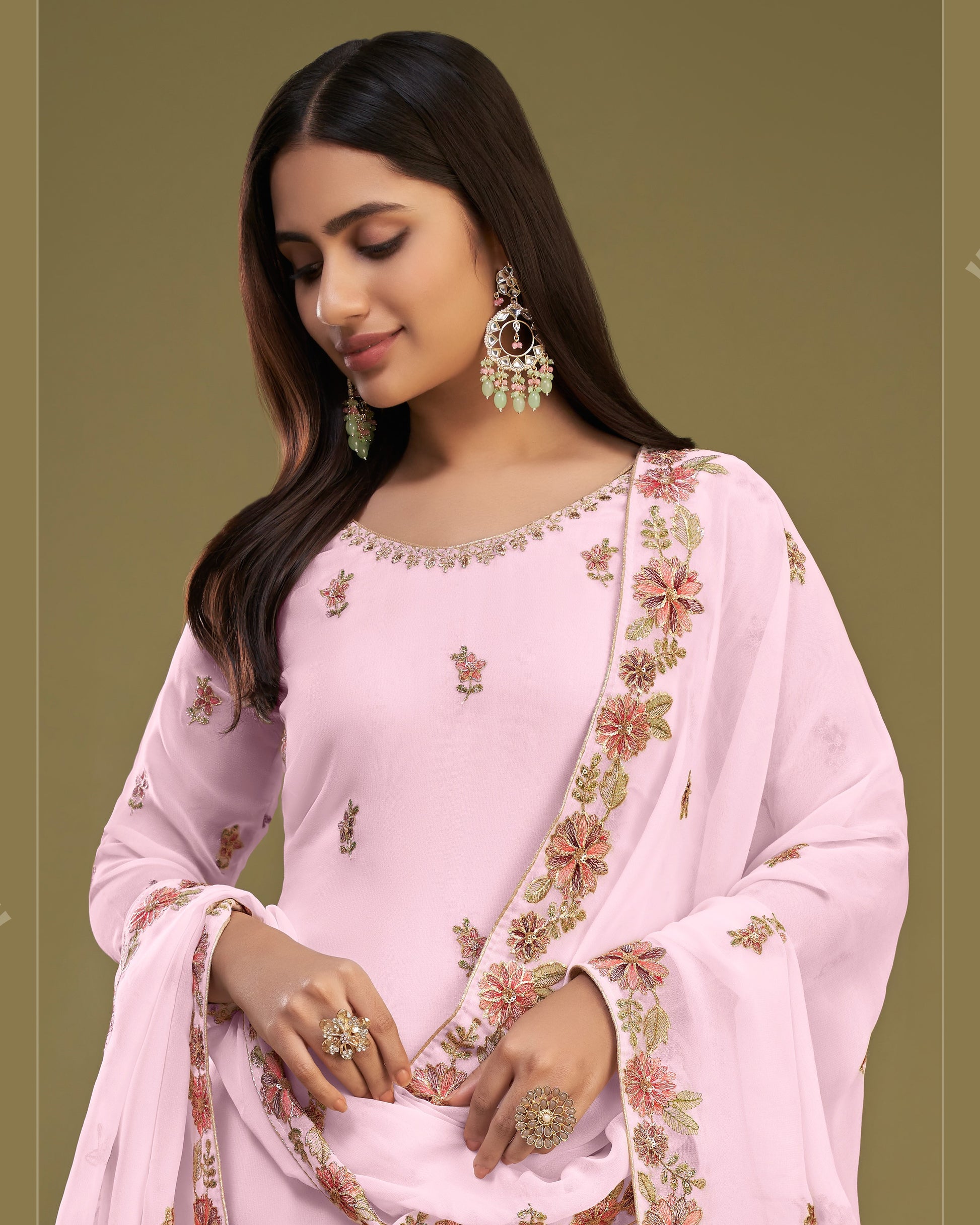 Woman wearing a pink embroidered traditional outfit with a green background