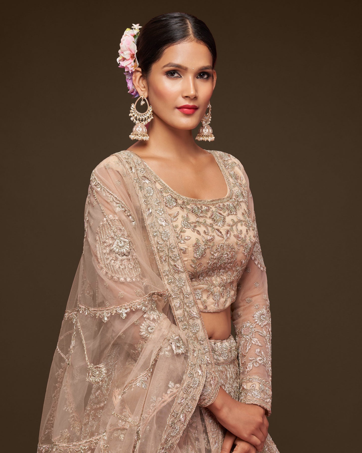 Woman wearing a traditional embroidered saree with a plain background