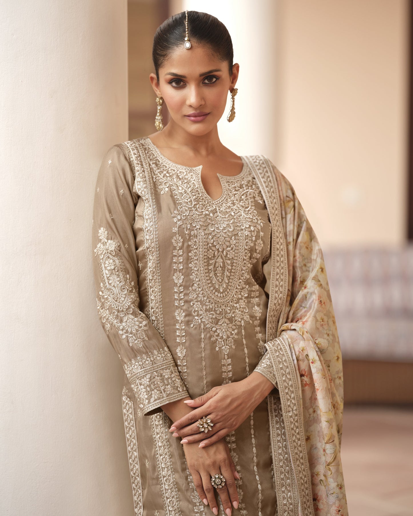Woman wearing a traditional embroidered outfit with a plain background