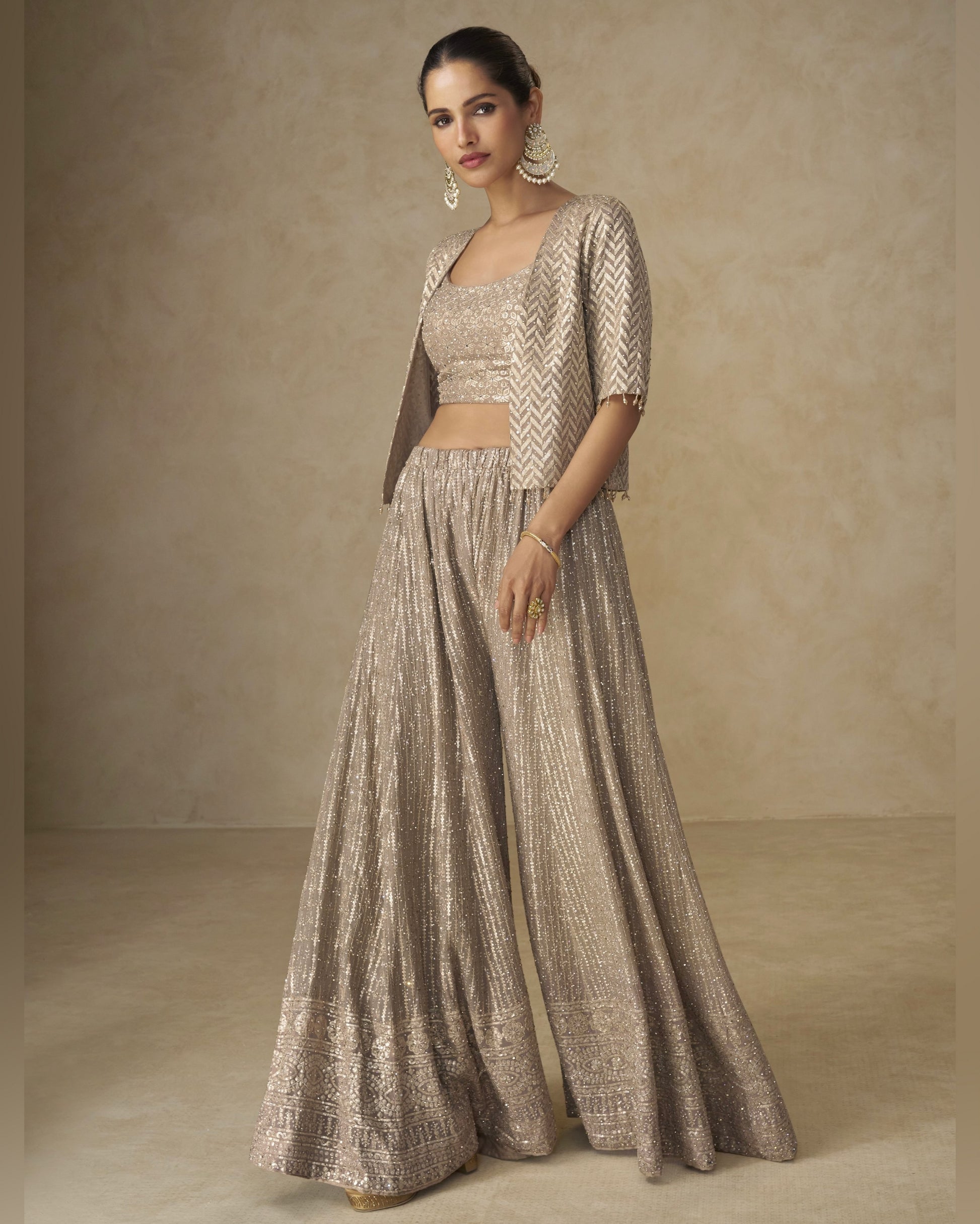 Woman wearing a traditional outfit with a beige and brown pattern against a neutral background