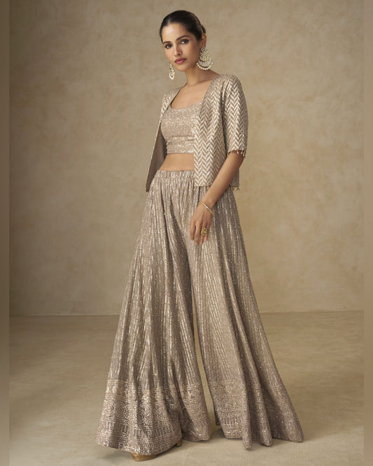 Woman wearing a traditional outfit with a beige and brown pattern against a neutral background