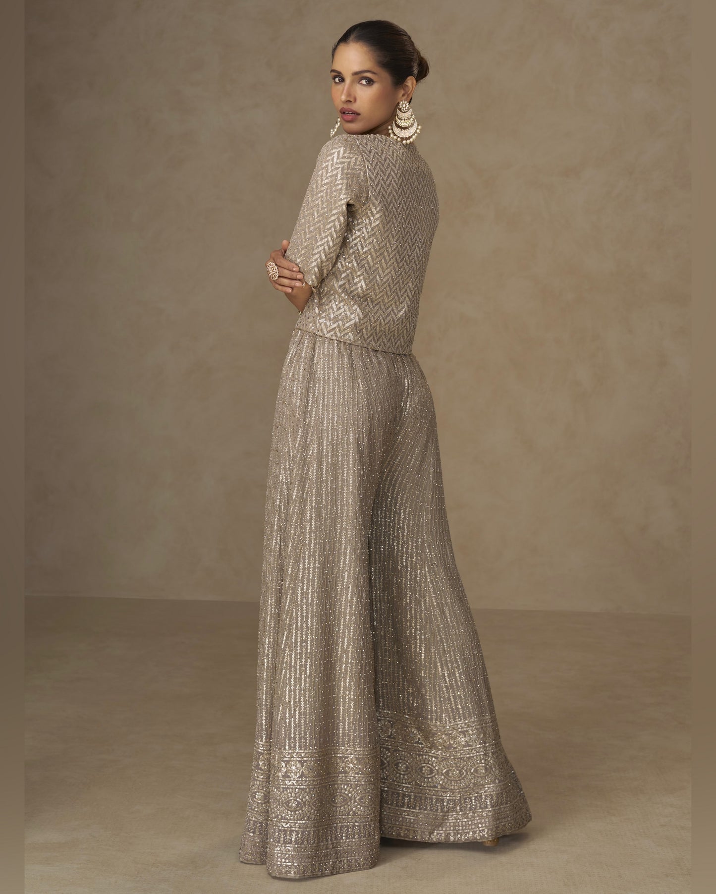 Woman wearing a metallic silver outfit against a brown background