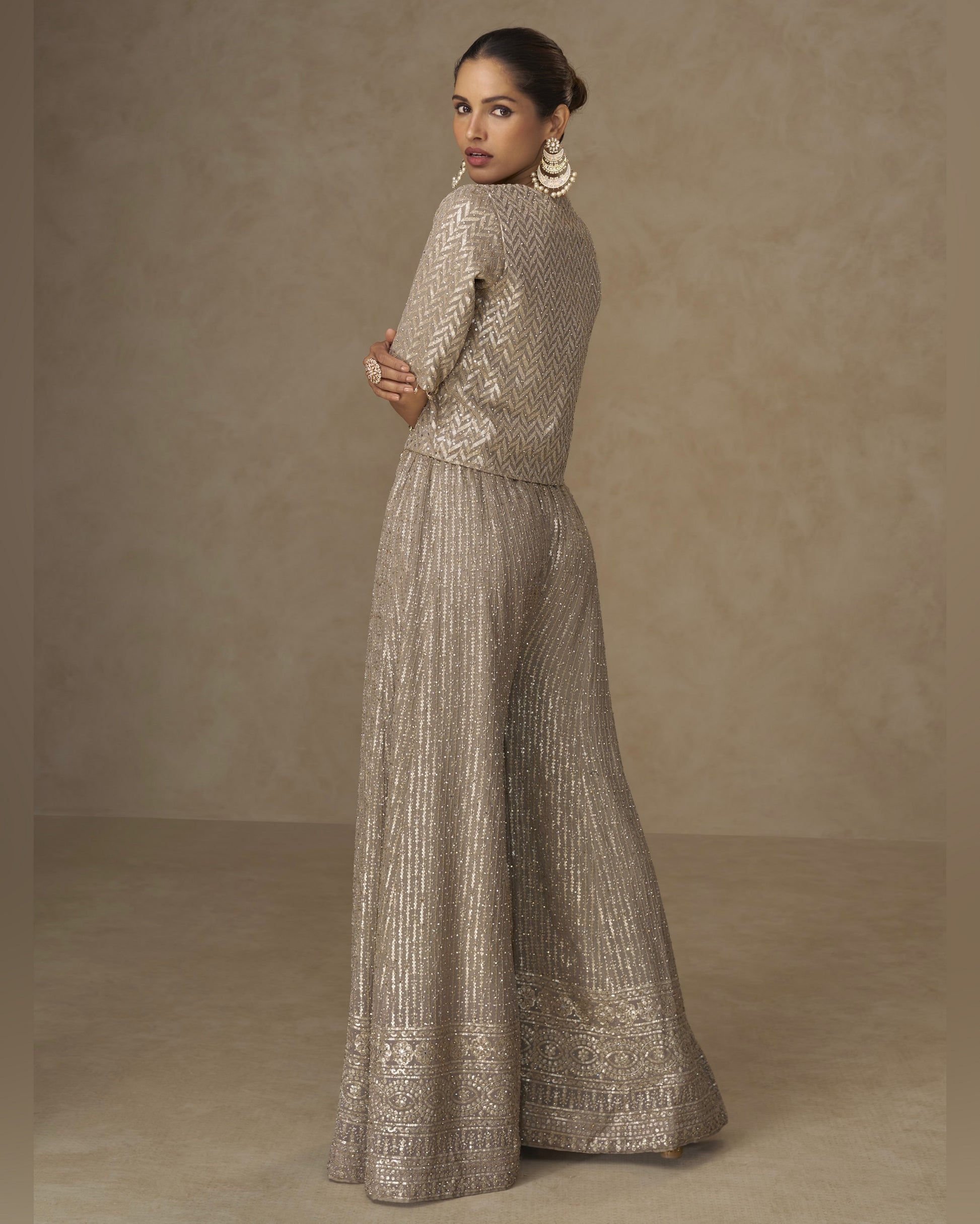 Woman wearing a metallic silver outfit against a brown background