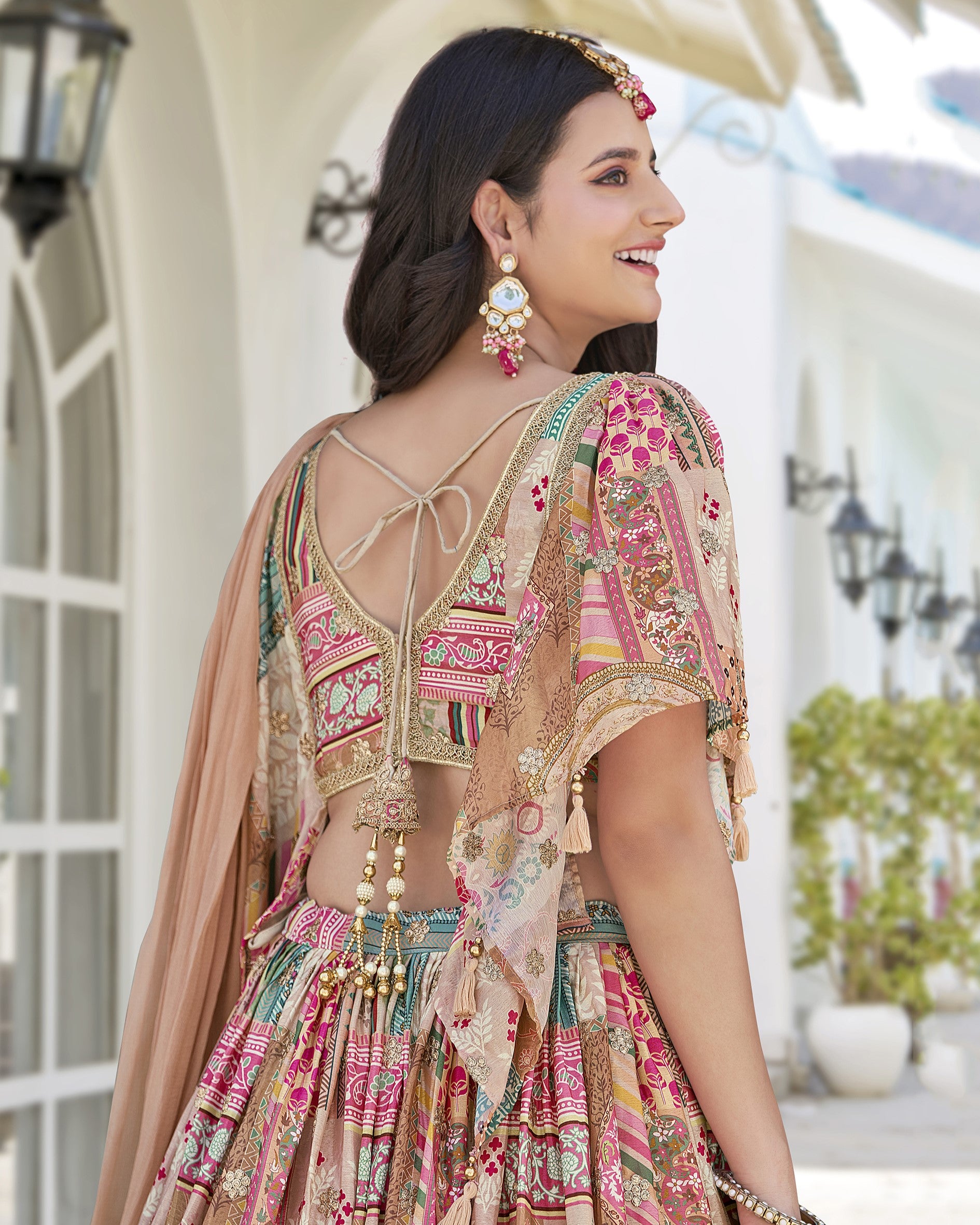 Woman wearing a colorful traditional outfit with intricate patterns in an outdoor setting.