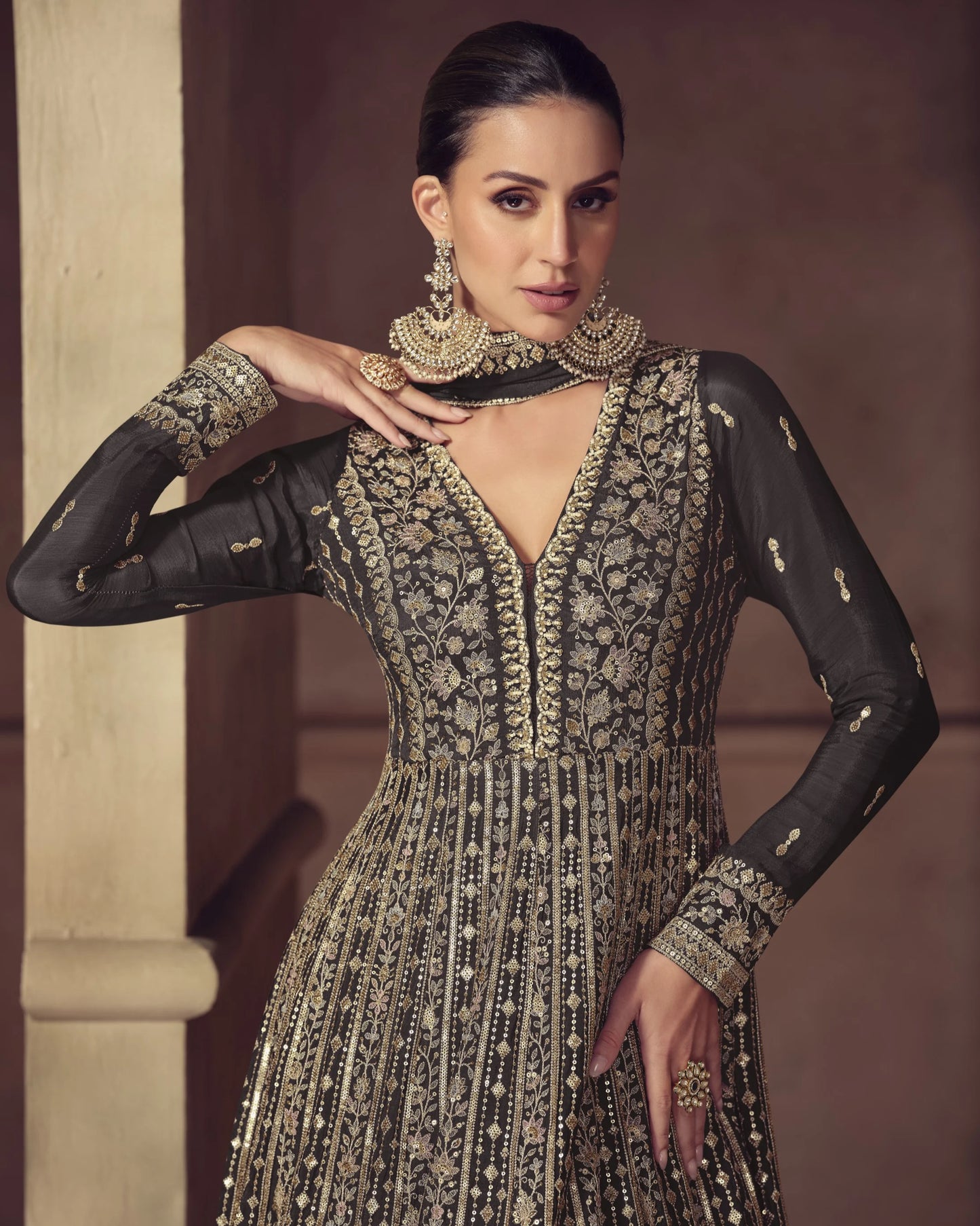 Woman wearing an ornate black and gold traditional outfit with jewelry against a neutral background