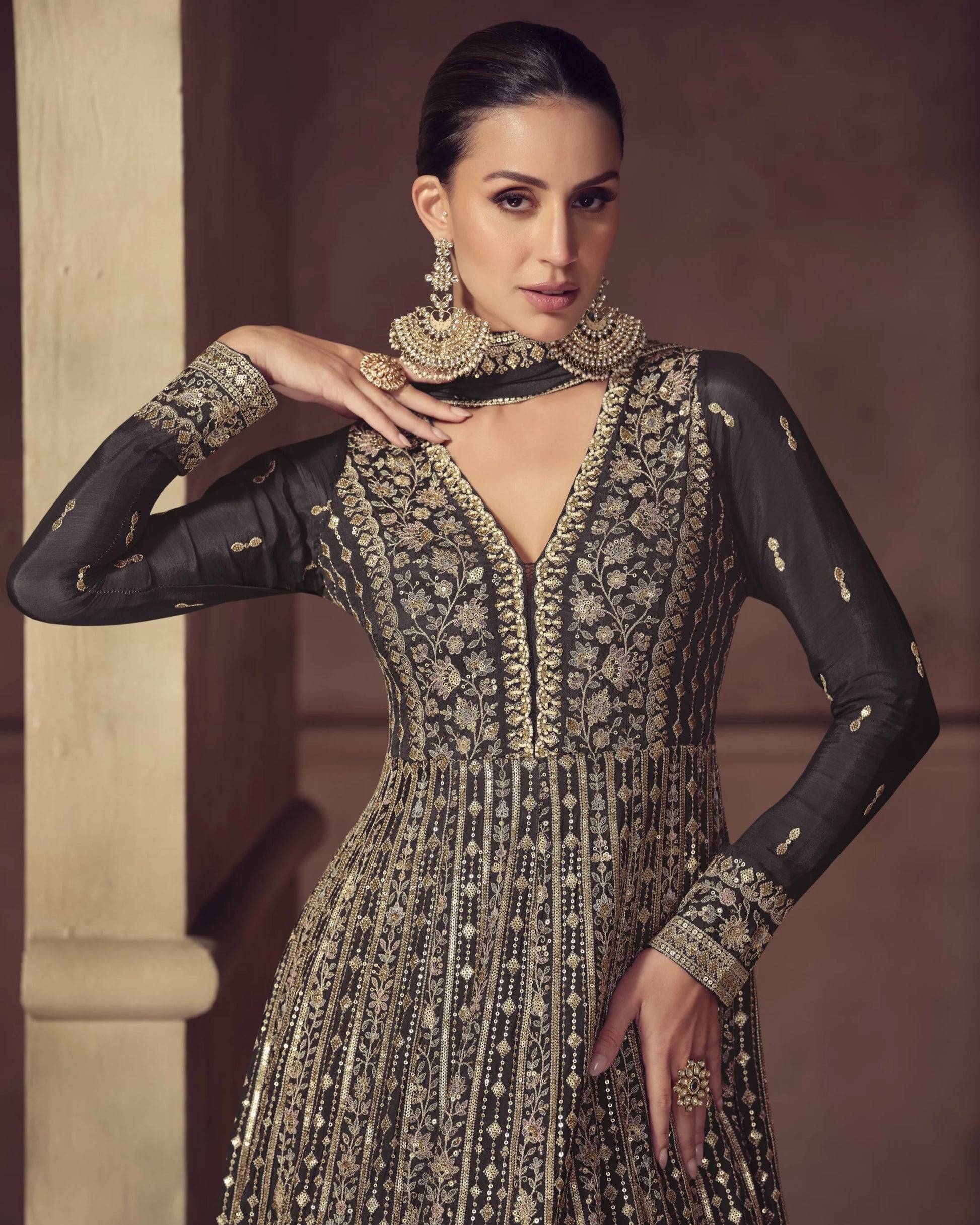 Woman wearing an ornate black and gold traditional outfit with jewelry against a neutral background