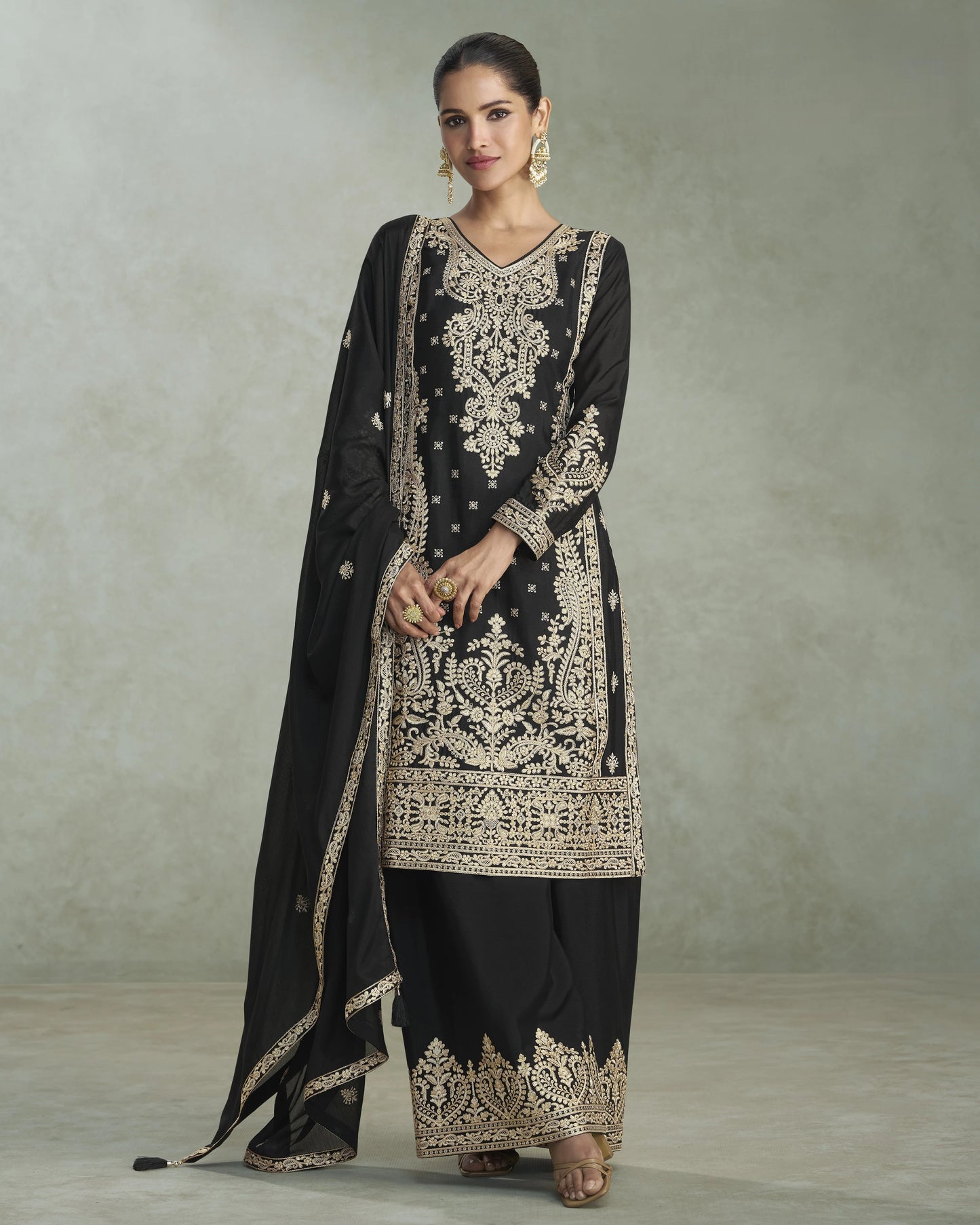 Woman wearing a black embroidered traditional outfit with a plain background