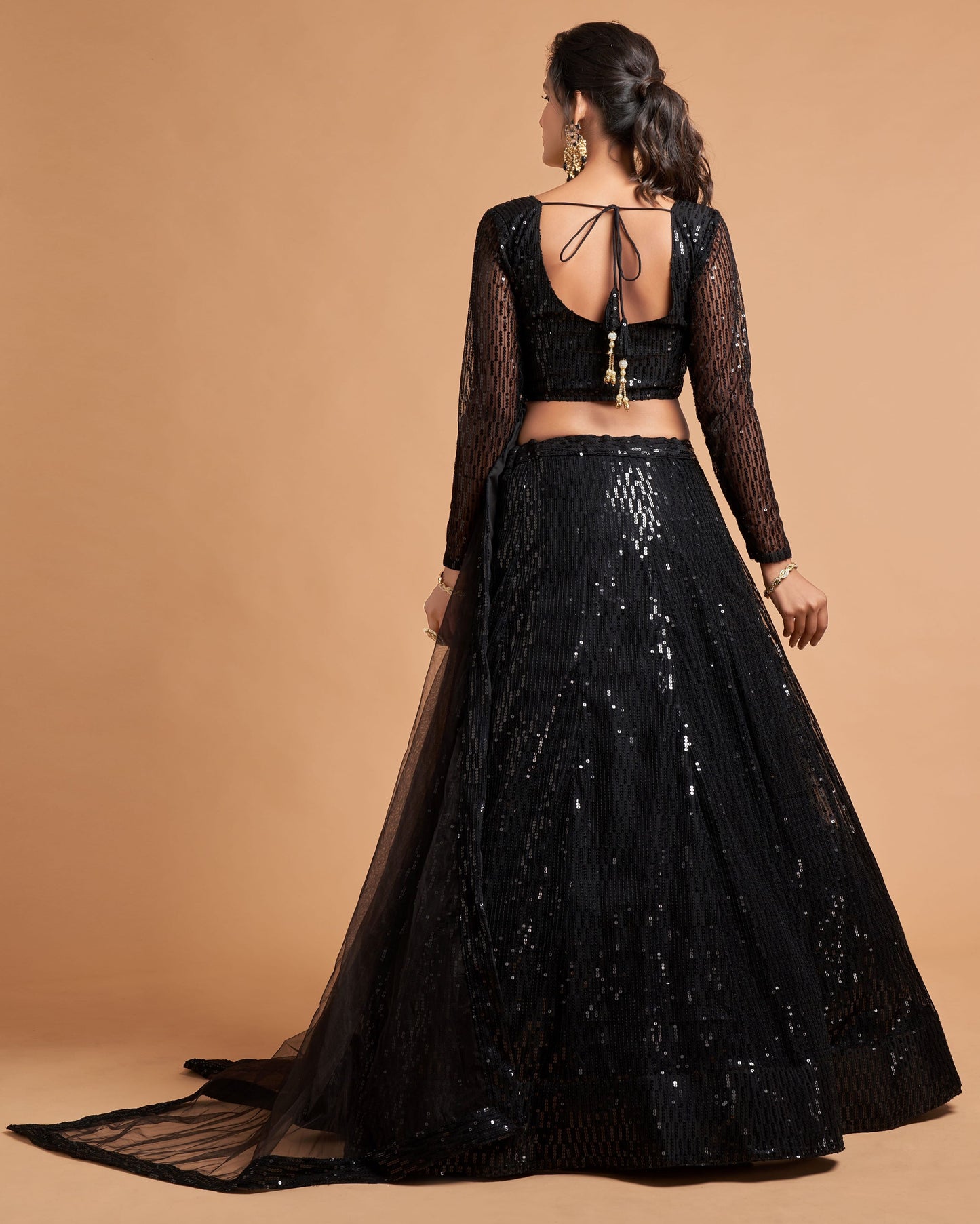 Black embroidered lehenga with sheer sleeves on a beige background