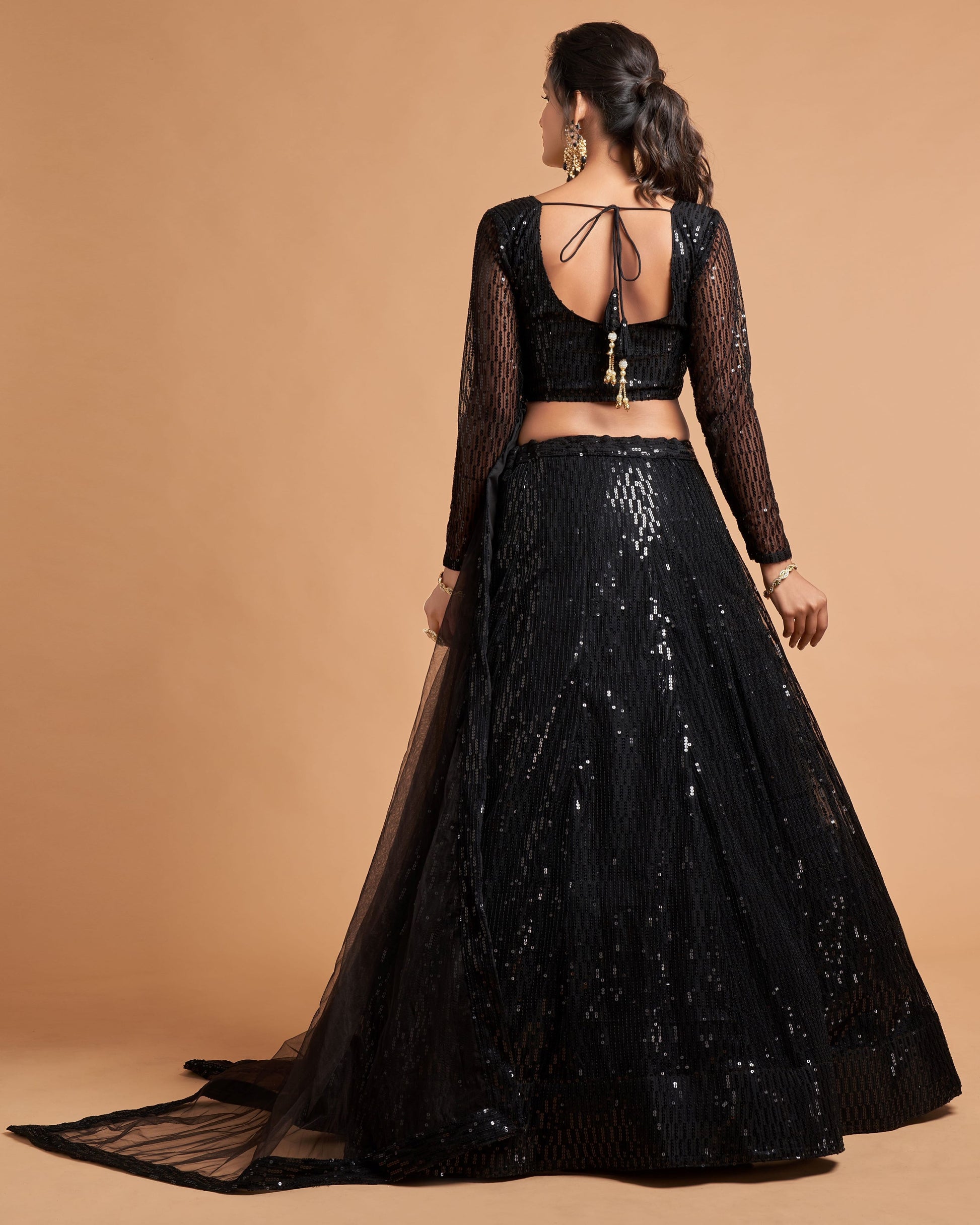 Black embroidered lehenga with sheer sleeves on a beige background