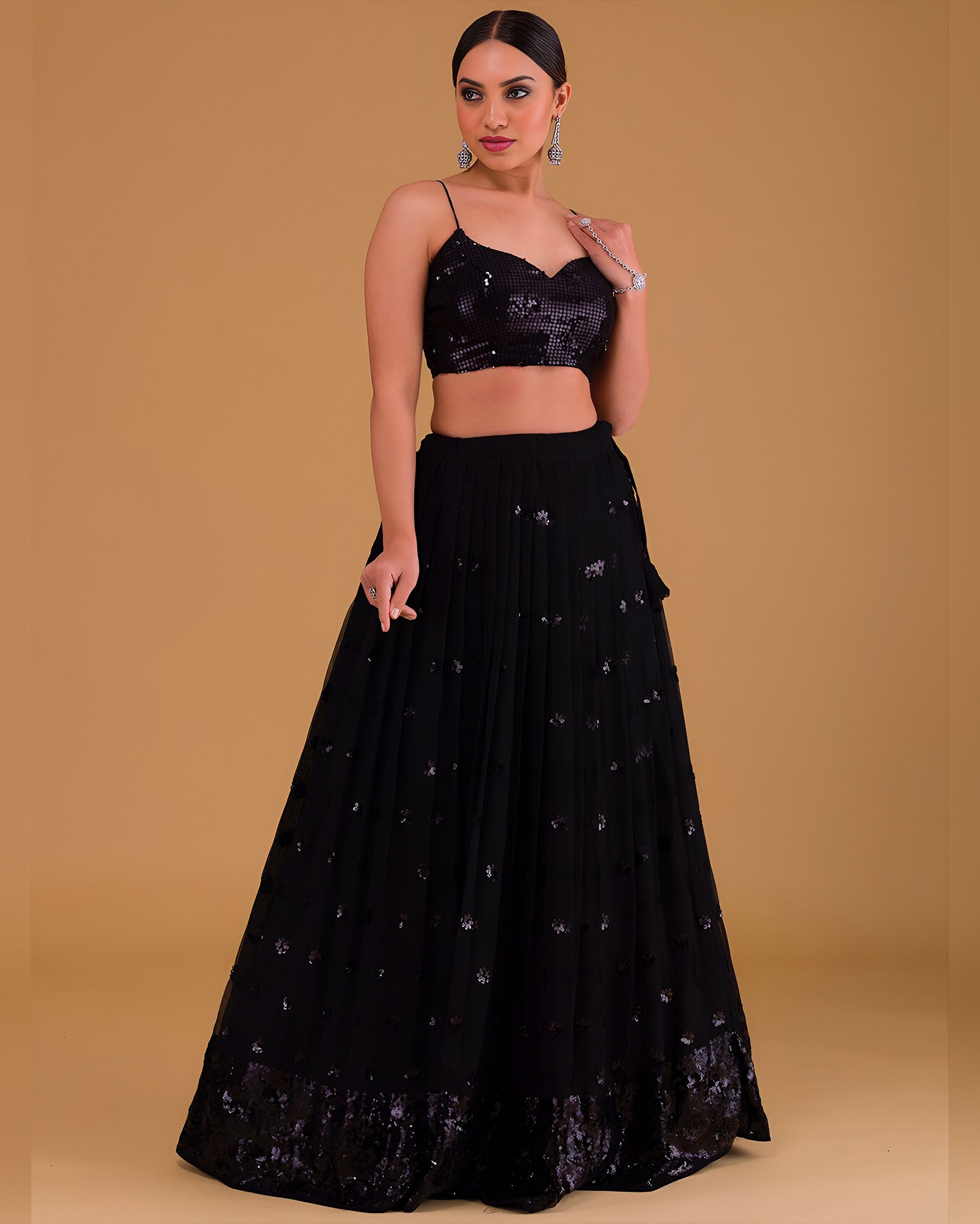 Woman wearing a black embroidered lehenga with a matching top against a beige background