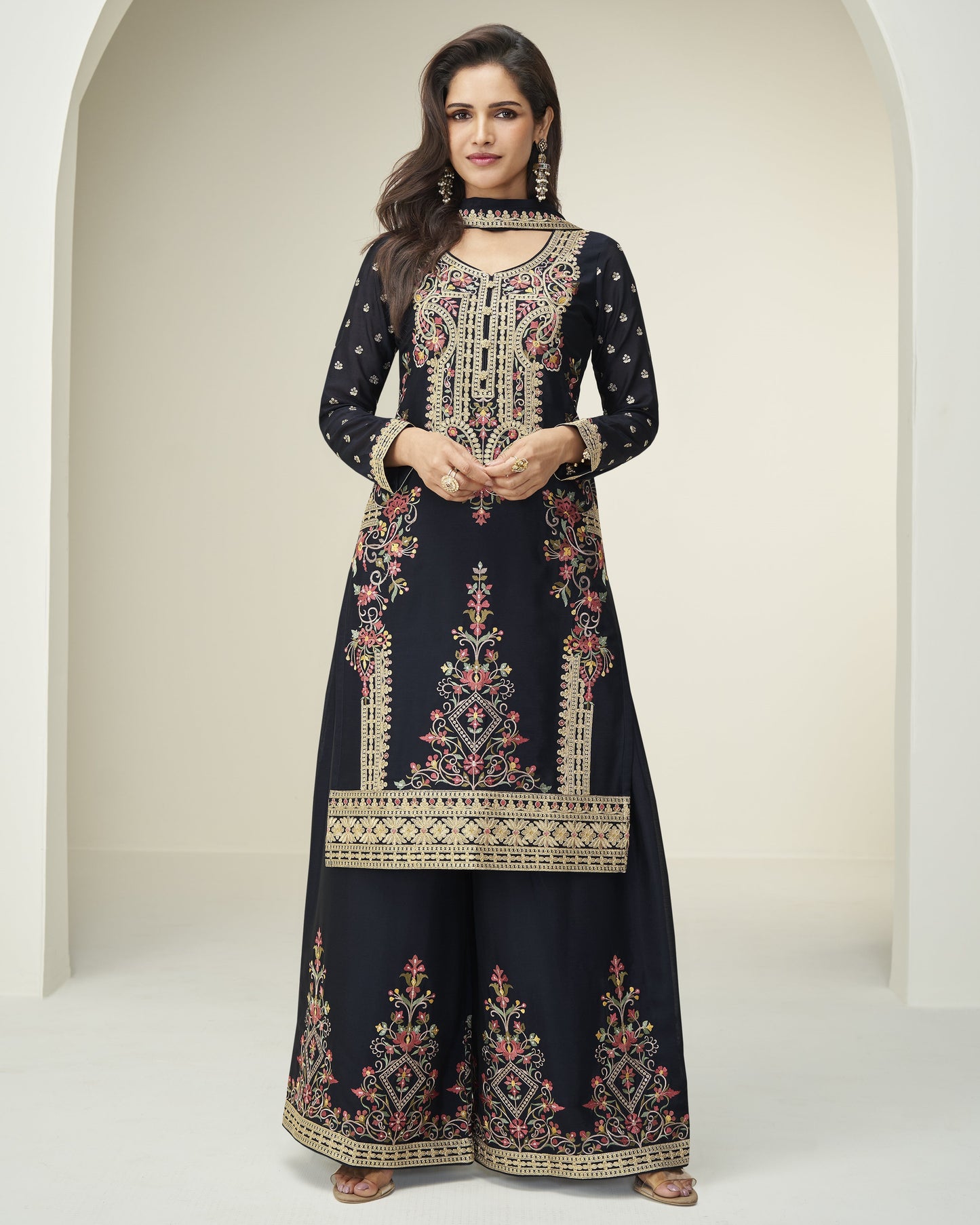 Woman wearing a navy blue embroidered dress with a white background