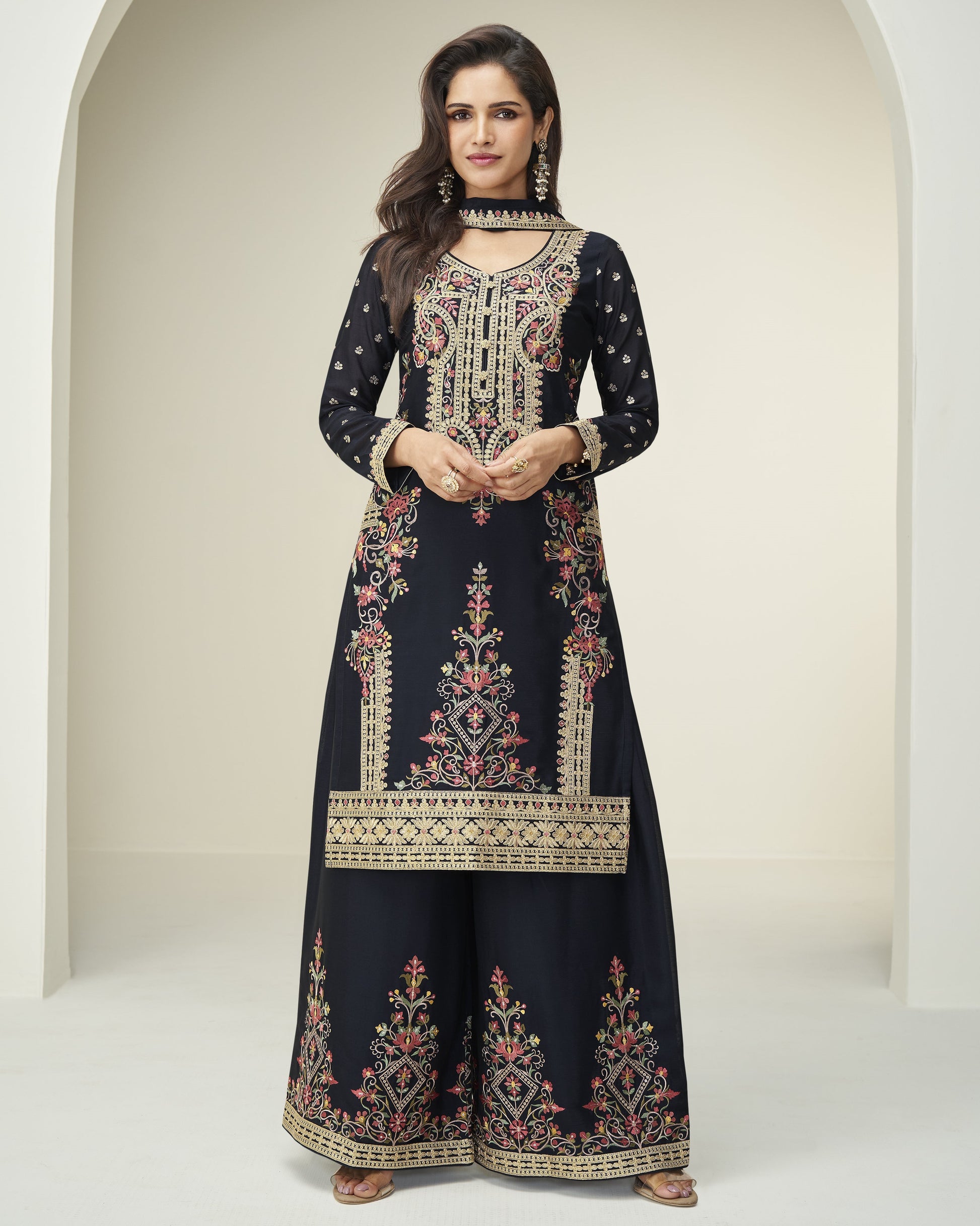 Woman wearing a navy blue embroidered dress with a white background