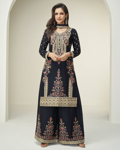 Woman wearing a navy blue embroidered dress with a white background