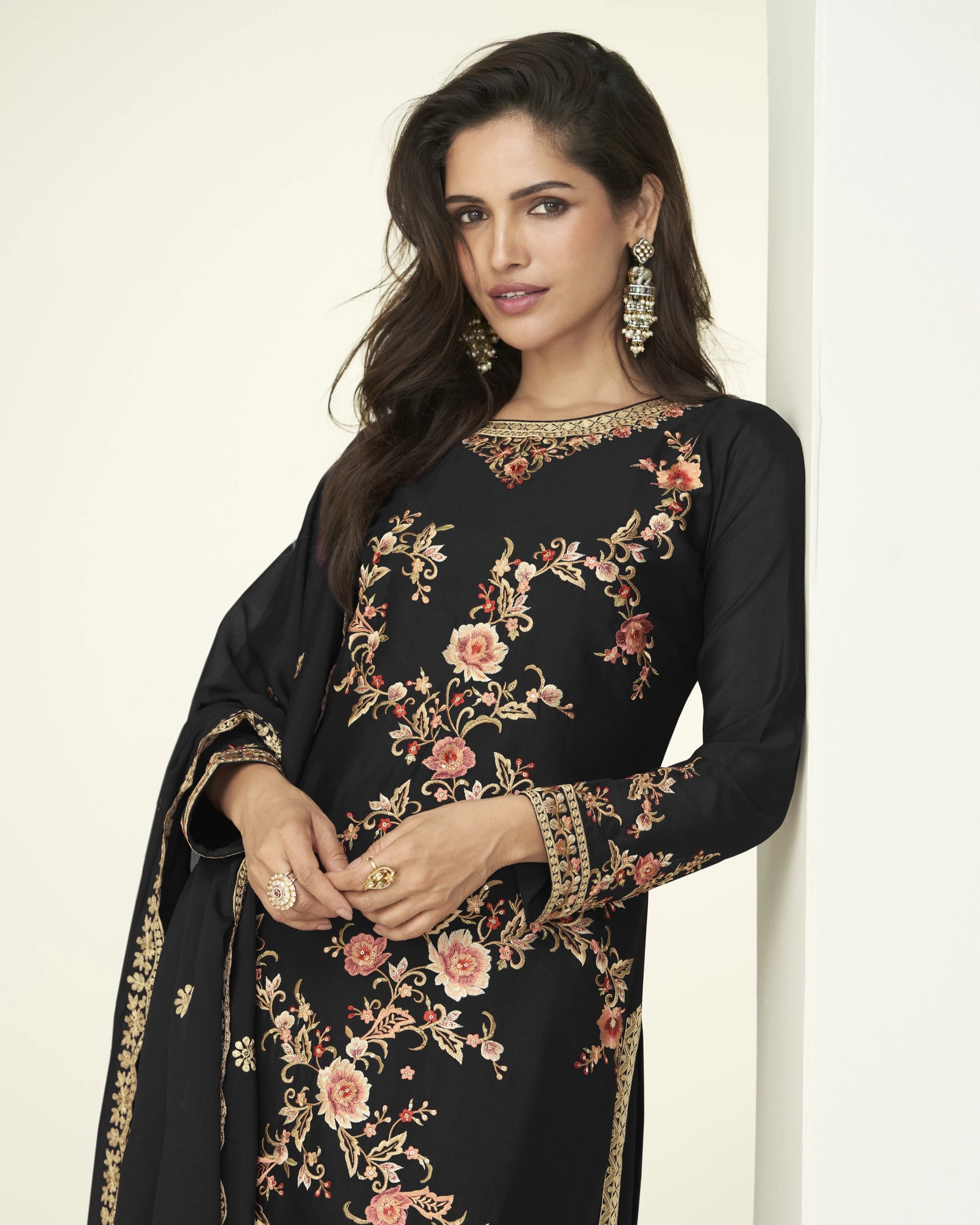 Woman wearing a black embroidered dress with floral patterns on a white background