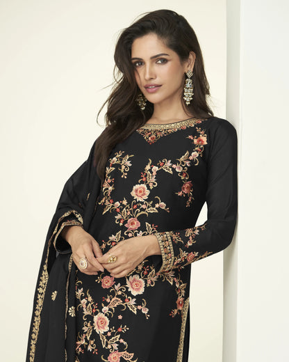 Woman wearing a black embroidered dress with floral patterns on a white background