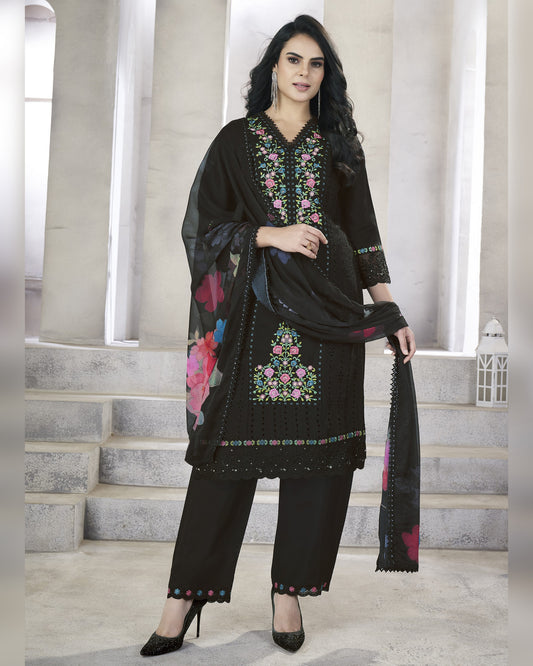 Woman wearing a black embroidered outfit with a scarf in an indoor setting