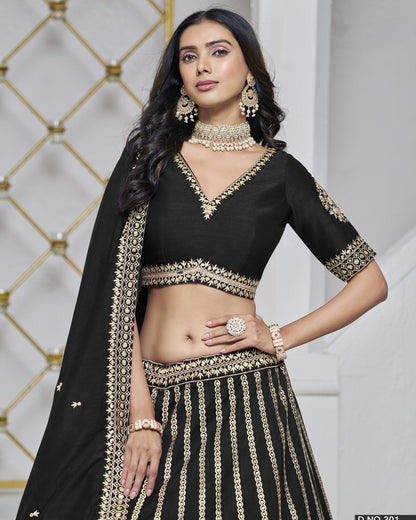 Woman wearing a black and gold traditional outfit with jewelry against a decorative wall.