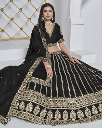 Woman in a black and gold embroidered traditional outfit sitting on a white surface.