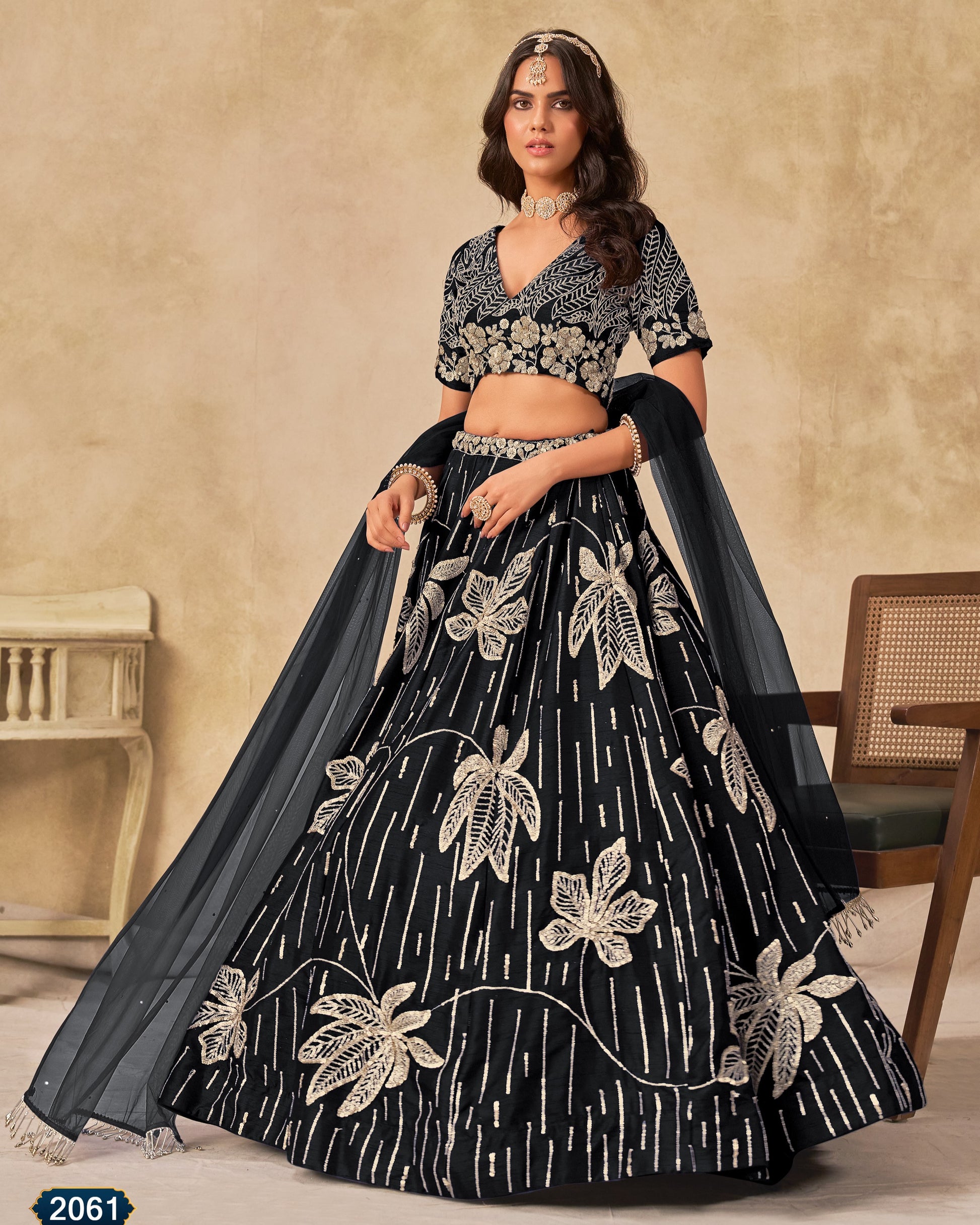 Woman wearing a black and white embroidered lehenga with a beige background