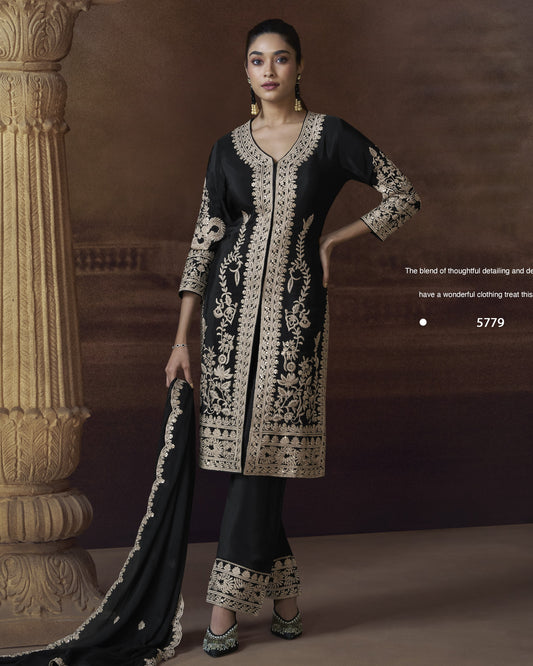 Woman wearing a black and white embroidered traditional outfit against a brown background