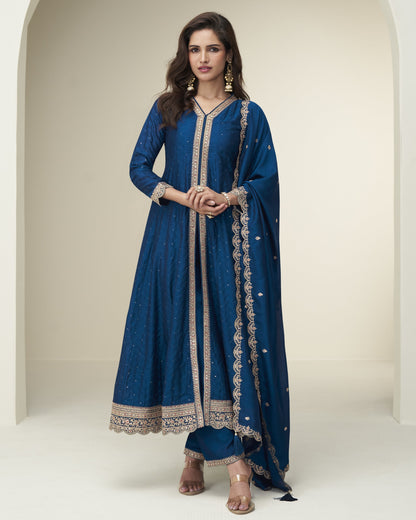 Woman wearing a blue traditional outfit with intricate designs on a plain background