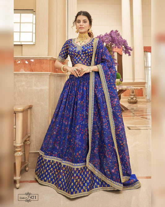 Woman wearing a blue traditional outfit with intricate patterns in an indoor setting.