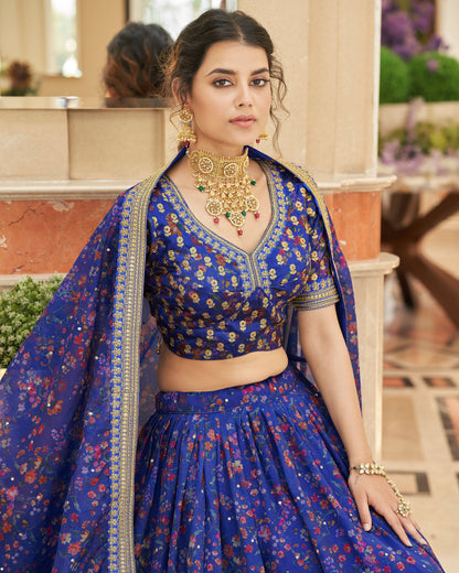 Woman in a blue traditional outfit with floral patterns in an indoor setting.