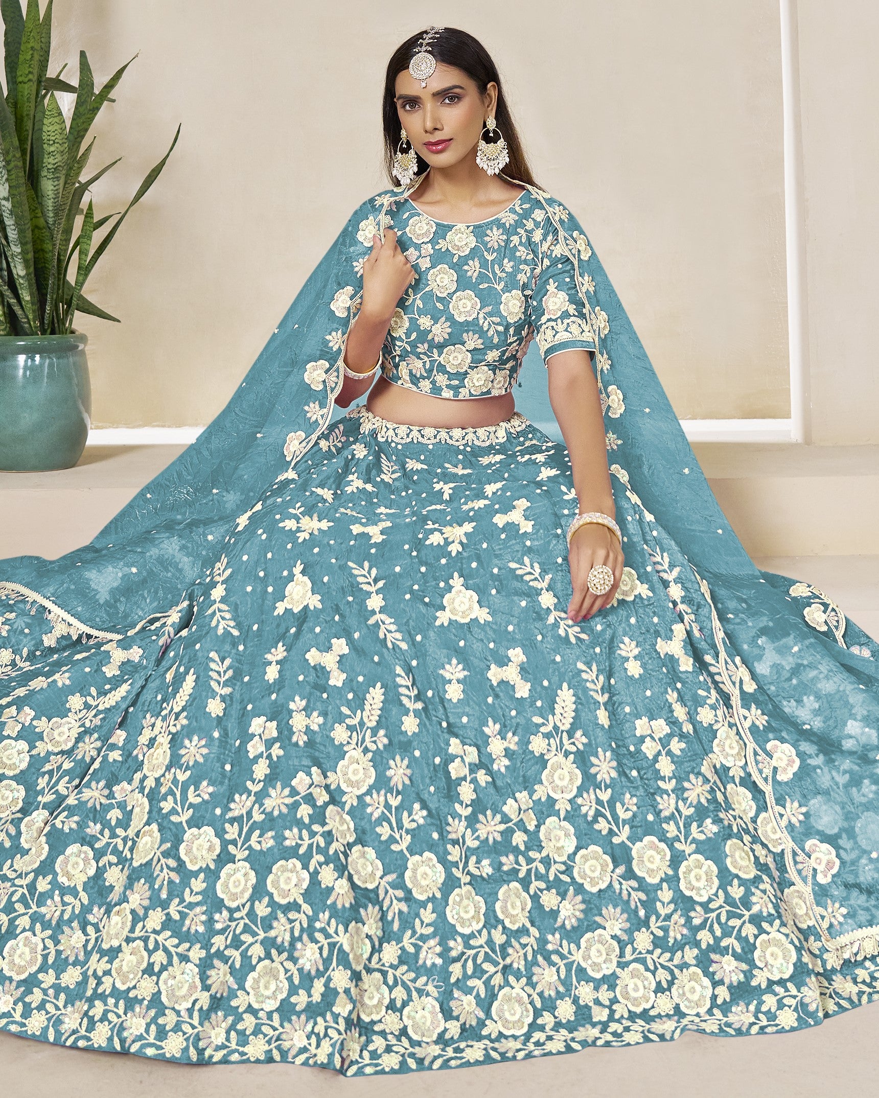 Woman wearing a blue floral lehenga with a white background