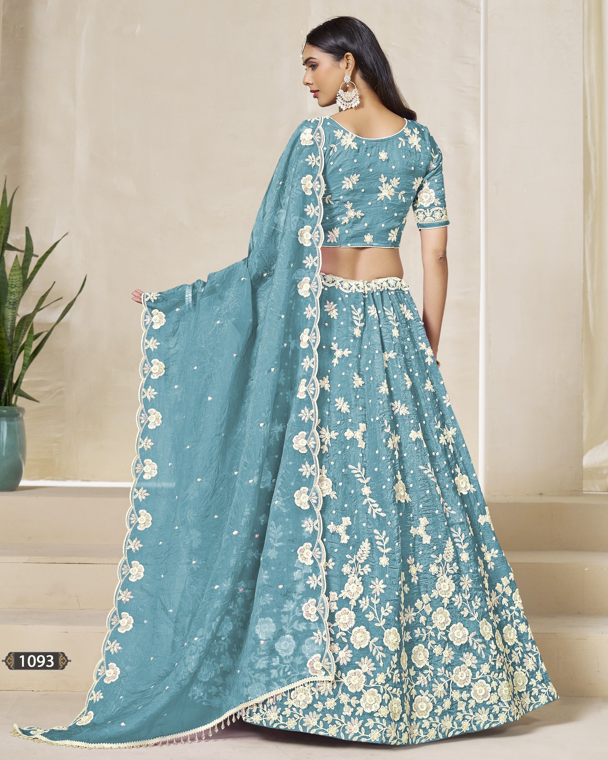 Woman wearing a teal embroidered saree with a matching blouse against a neutral background