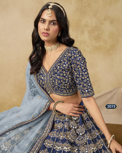 Woman wearing a traditional blue and gold embroidered outfit with a beige background