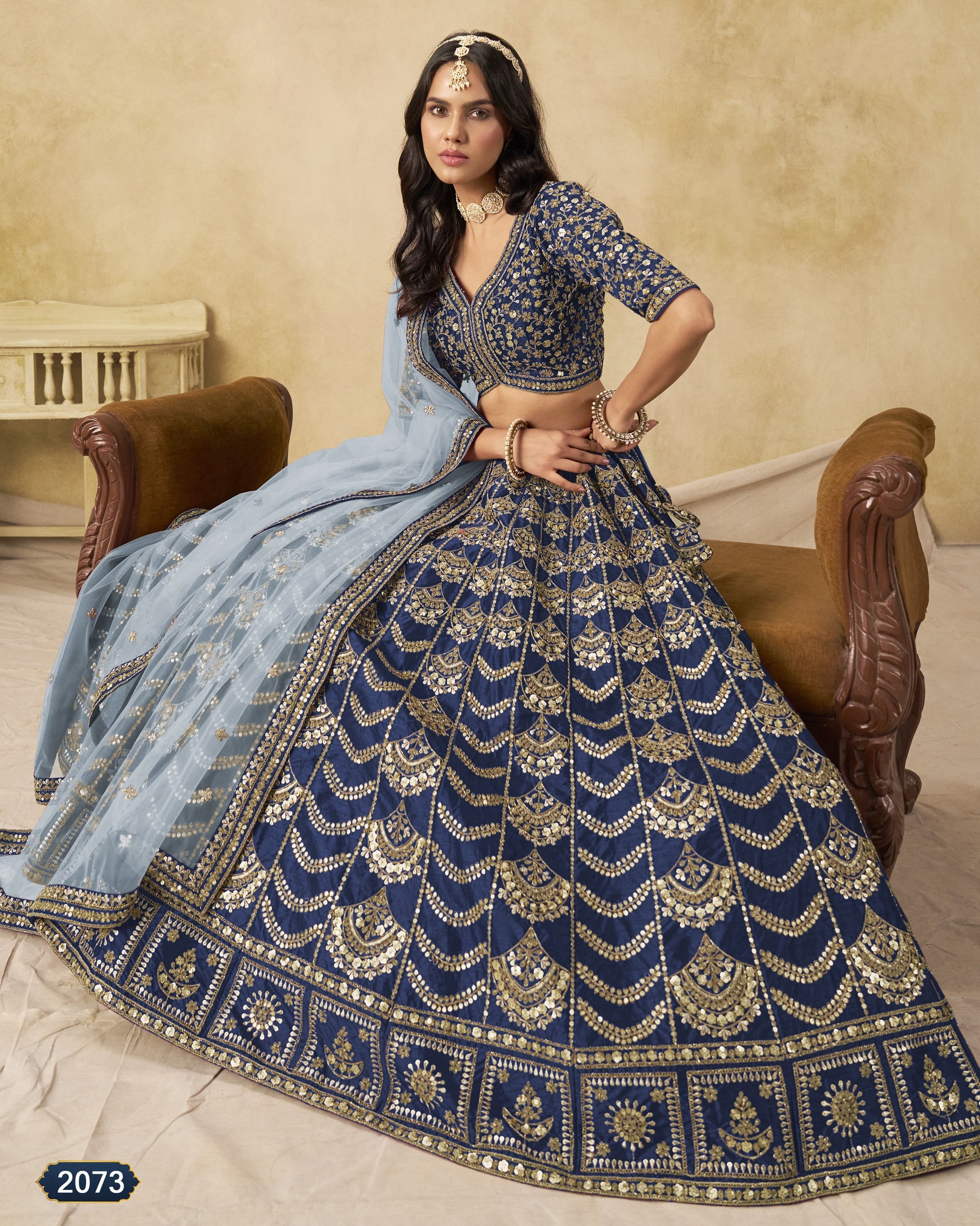 Woman wearing a blue and gold embroidered traditional outfit with a beige background