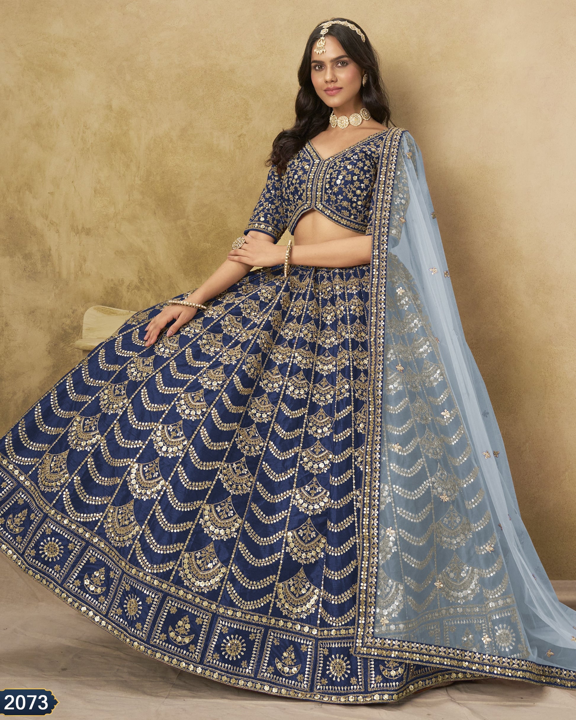Woman wearing a blue and gold embroidered traditional outfit with a beige background