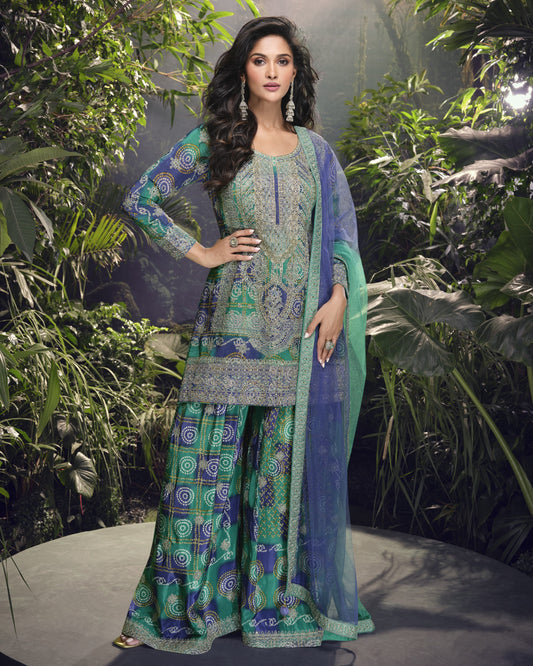 Woman in a traditional green and blue outfit with a floral pattern against a natural background