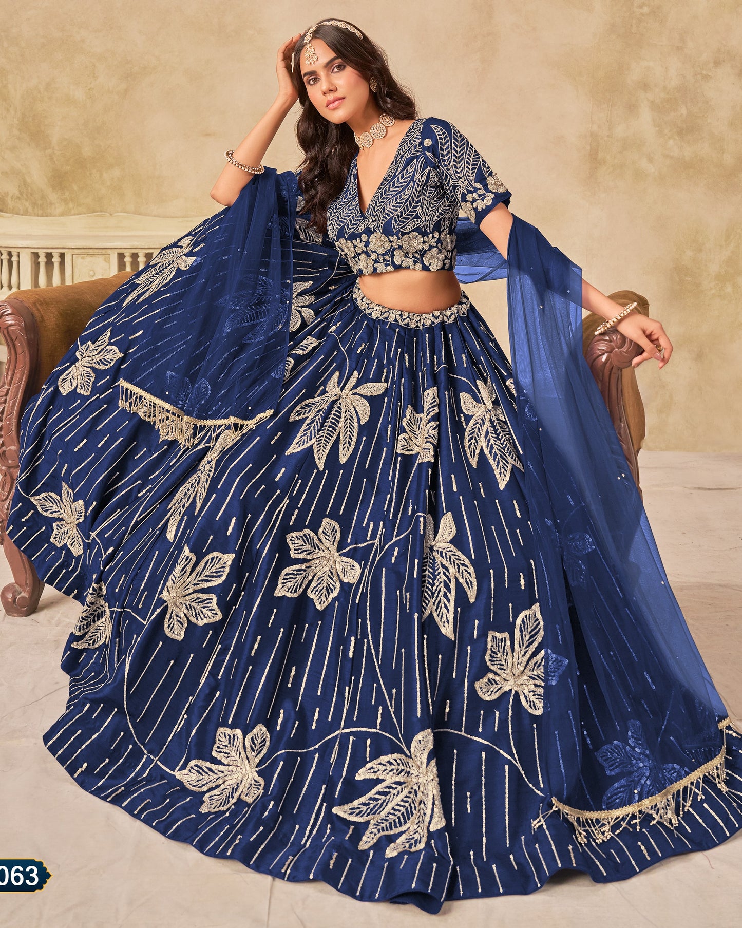 Woman wearing a blue embroidered lehenga with a beige background