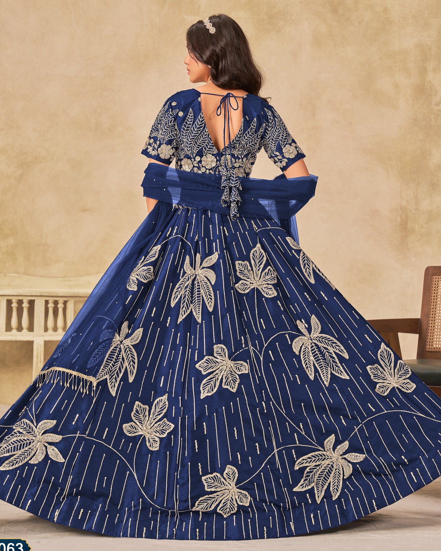 Woman wearing a blue embroidered dress with a beige background