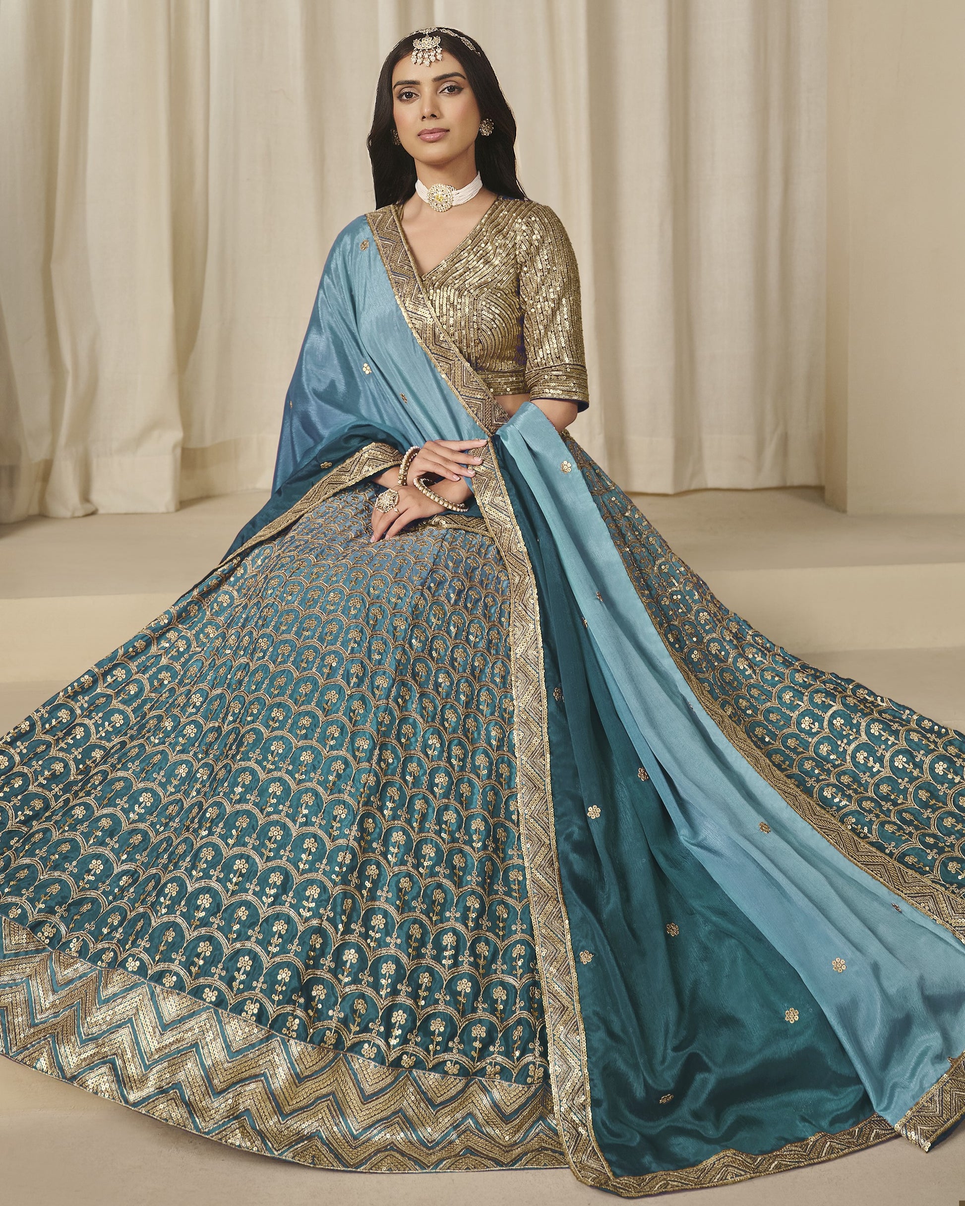 Woman wearing a traditional blue and gold saree with a plain background