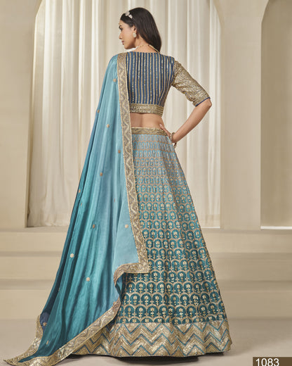 Woman wearing a blue and gold traditional outfit with a matching dupatta in a neutral setting.