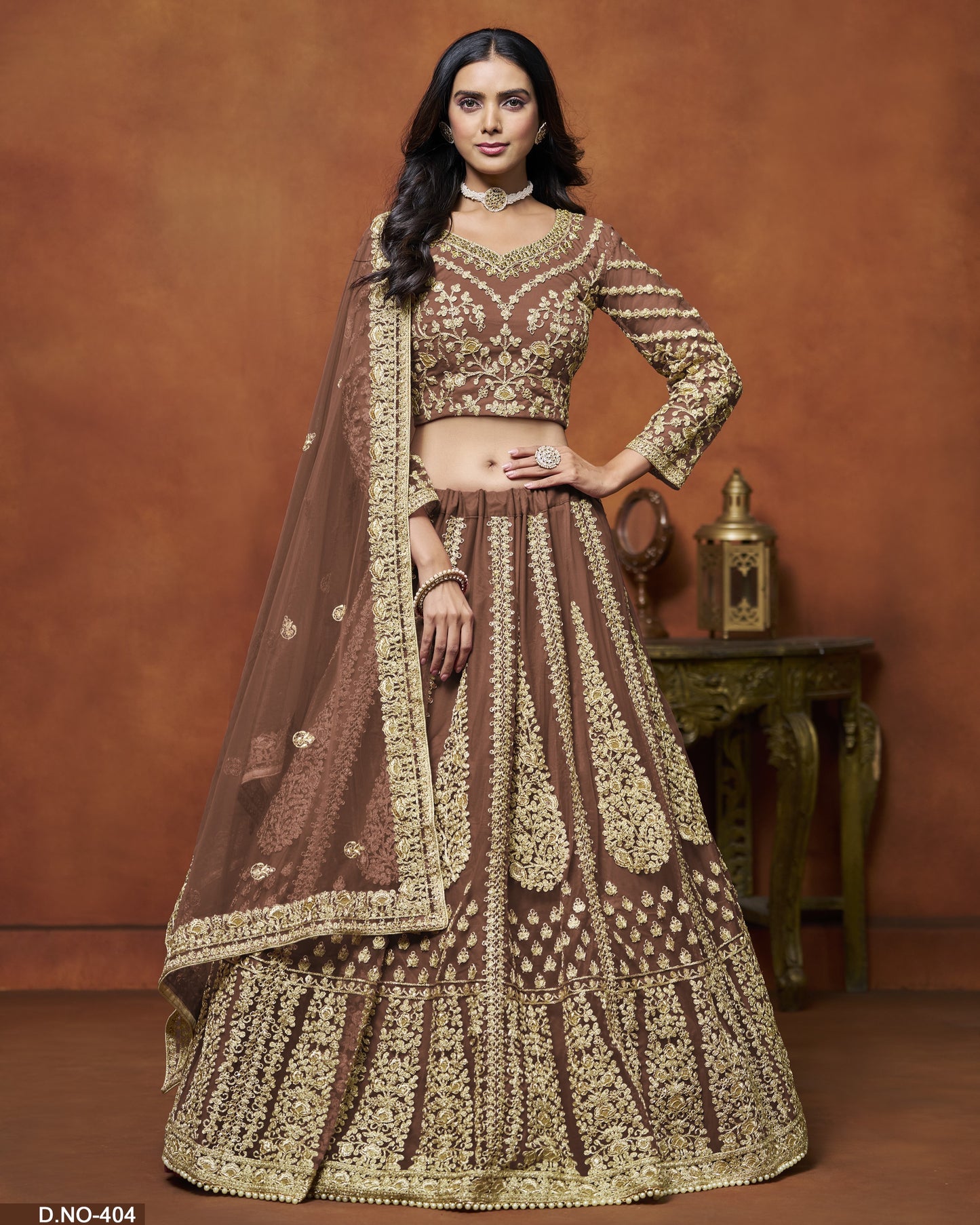 Woman wearing a traditional brown and gold embroidered outfit against a brown background