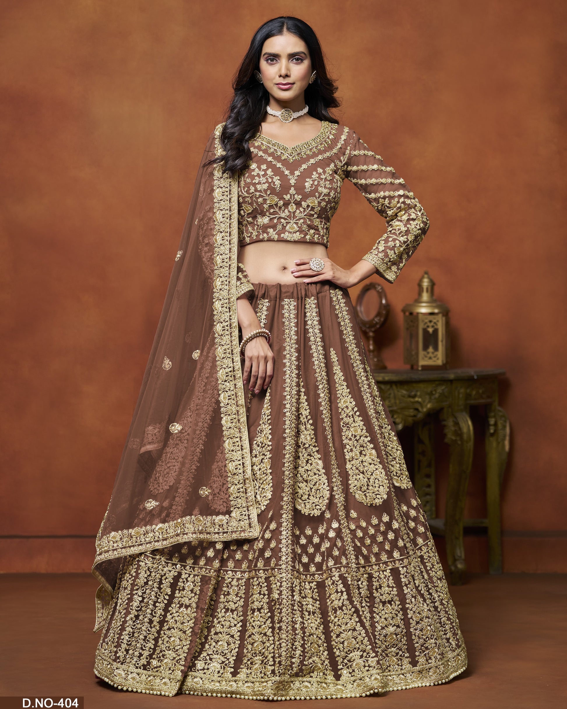 Woman wearing a traditional brown and gold embroidered outfit against a brown background