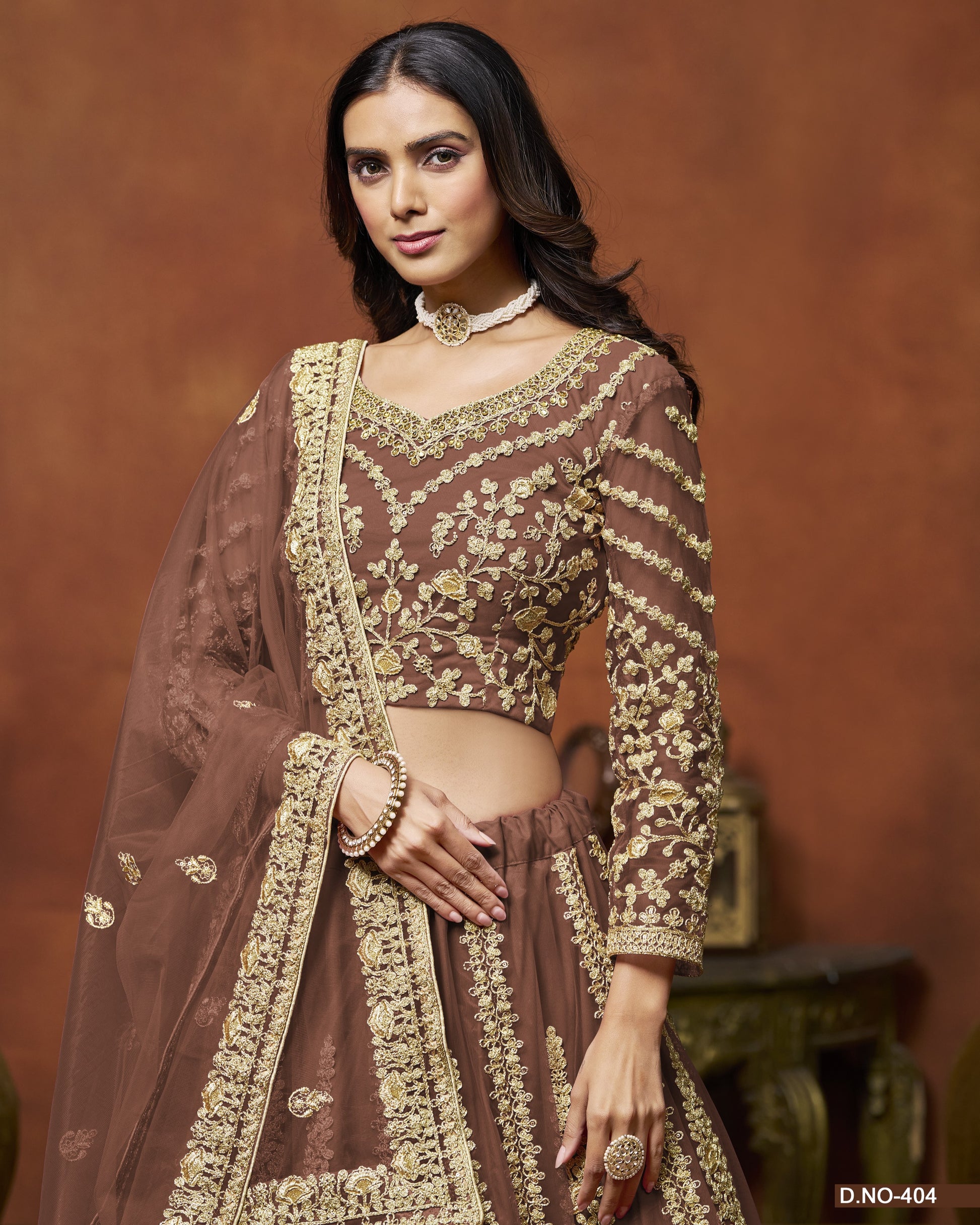Woman wearing a traditional brown and gold embroidered outfit against a warm-toned background